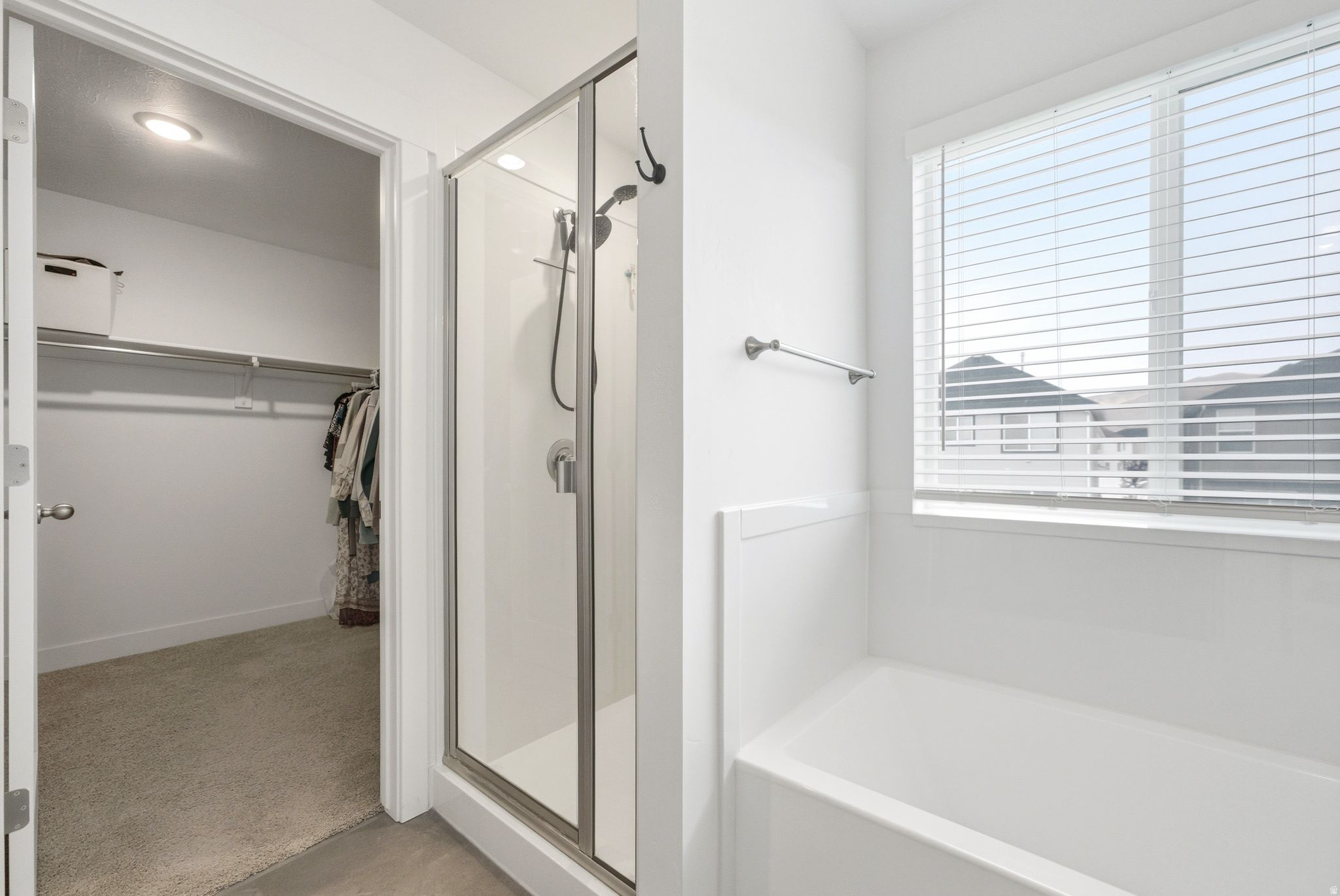 Contemporary bathroom featuring a glass-enclosed shower, white bathtub, and a window with blinds