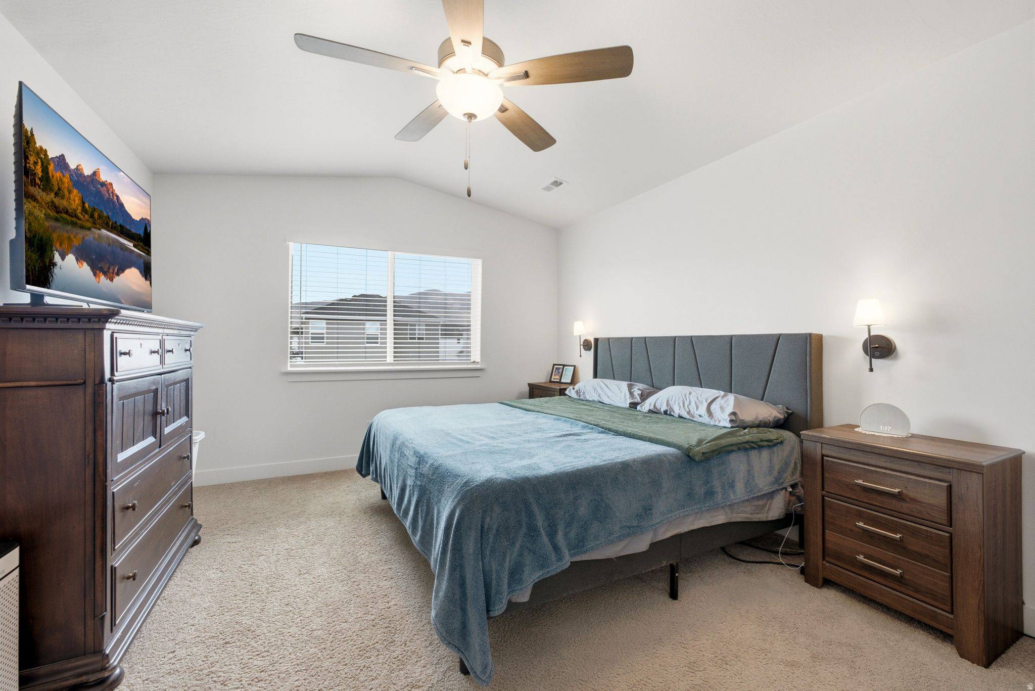 Bedroom featuring a vaulted ceiling with a ceiling fan, a window with horizontal blinds, and sconce lighting