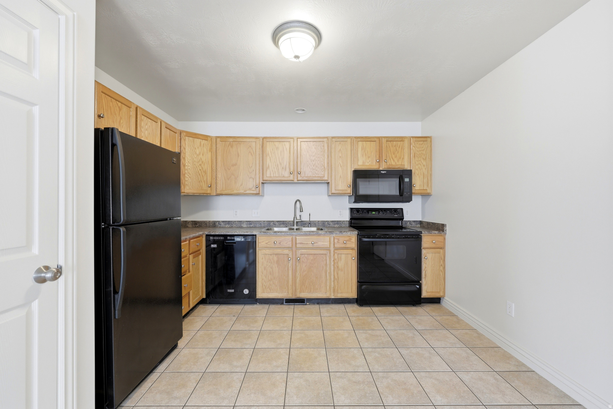 Kitchen featuring wood cabinetry, dark countertops, and tile flooring