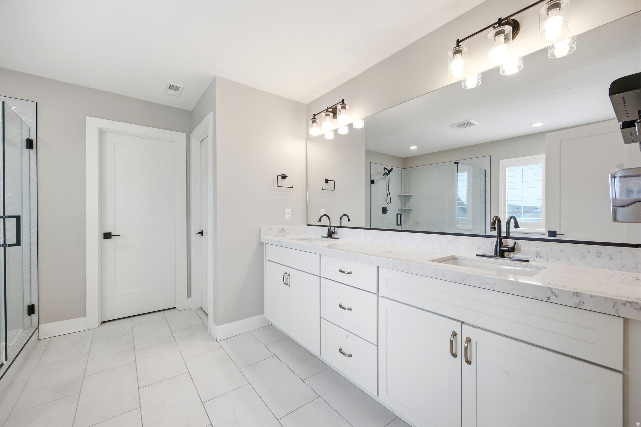 Bathroom featuring a dual vanity with white cabinetry, stone countertops, and undermount sinks