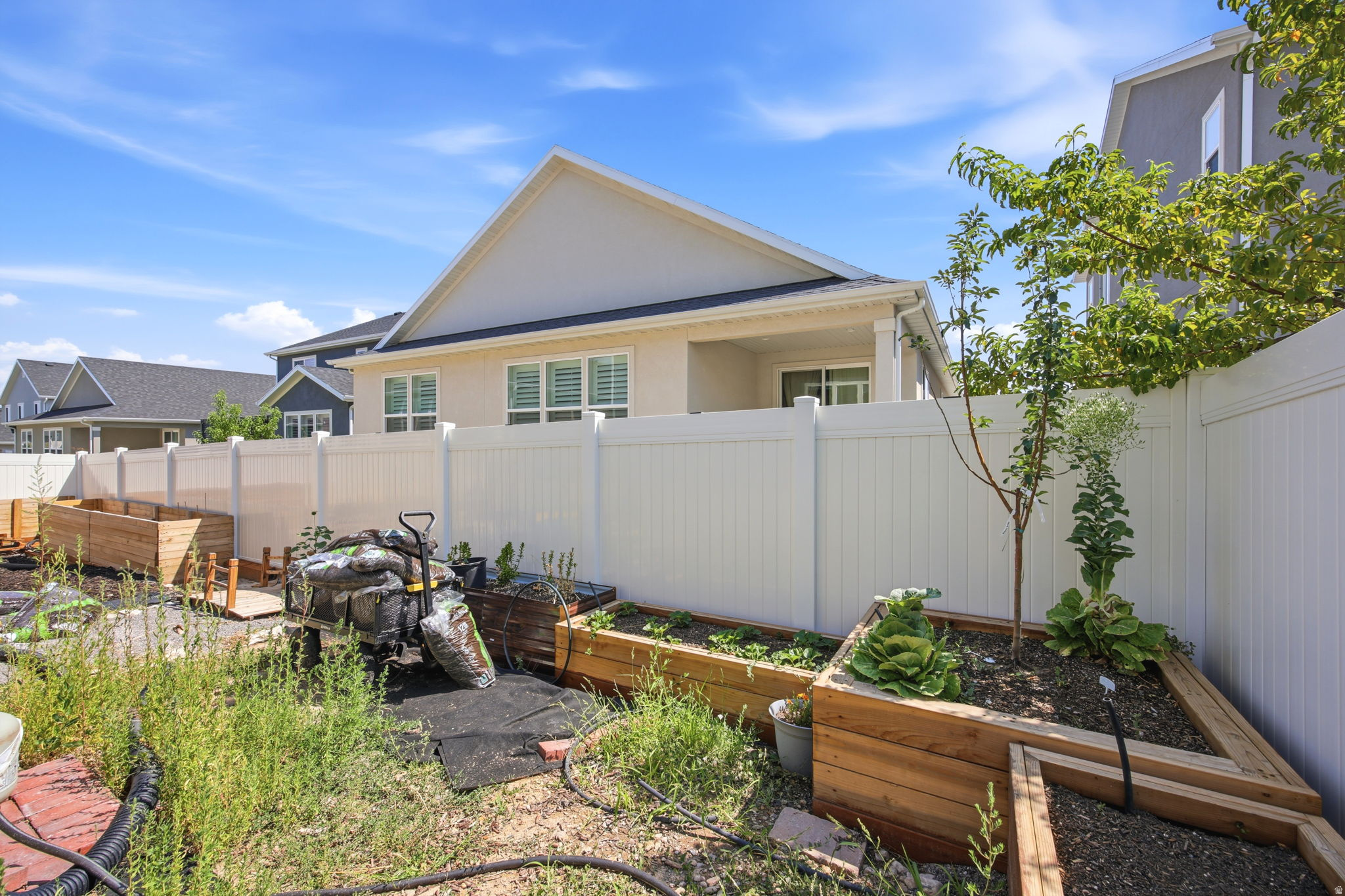 Private backyard space featuring a white vinyl fence, established garden beds, and mature trees