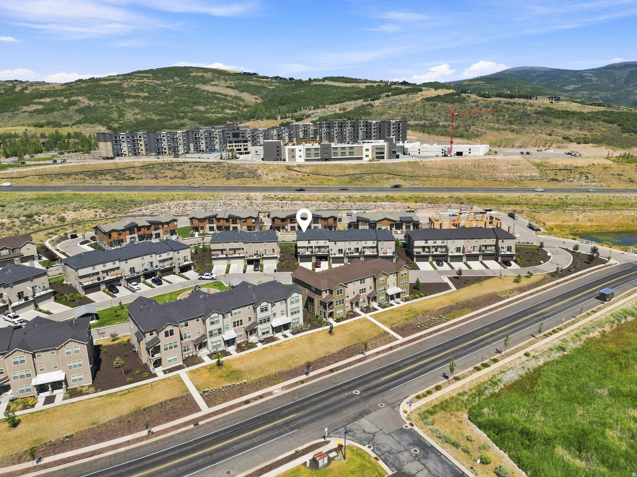 Aerial perspective showcasing a residential community with multi-story townhomes, structured roadways, and natural landscaping