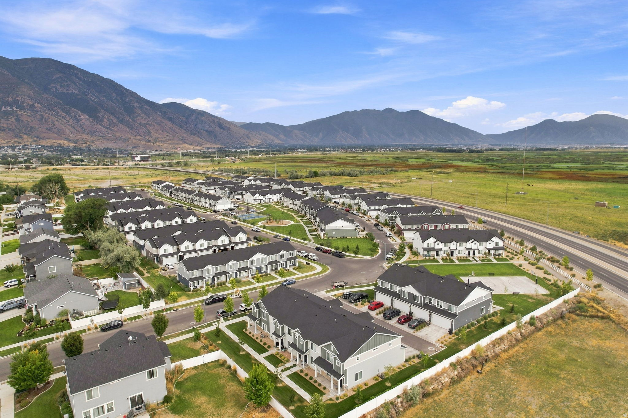 Aerial view of a planned residential community featuring multiple single-family homes with dark-pitched rooflines and light-colored exteriors