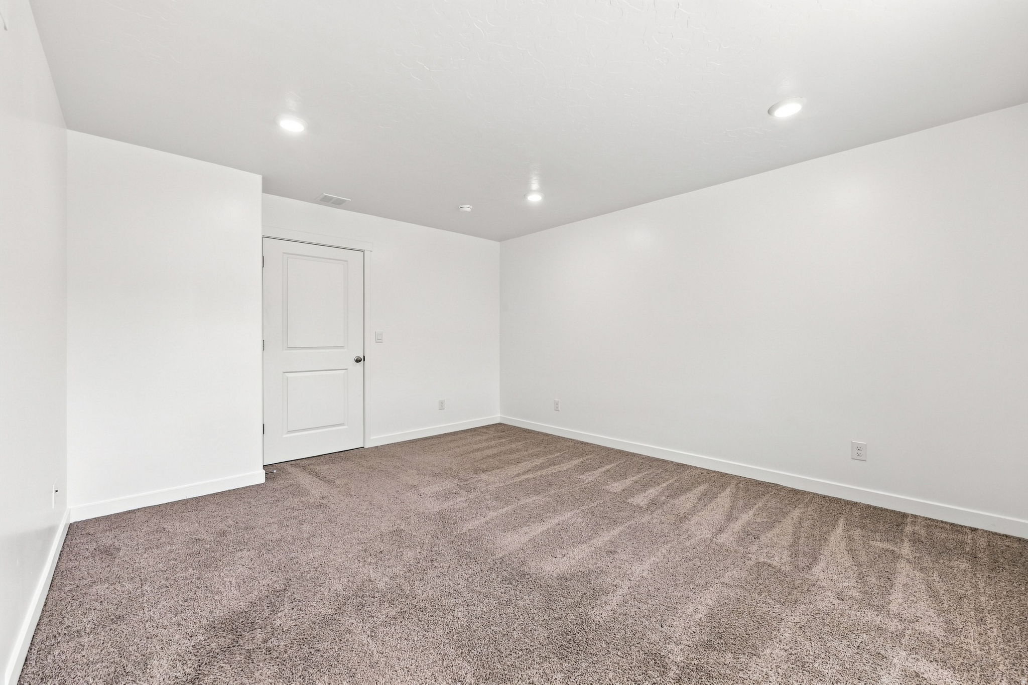 Spacious bedroom with neutral wall finishes, recessed ceiling lighting, and plush carpeting throughout