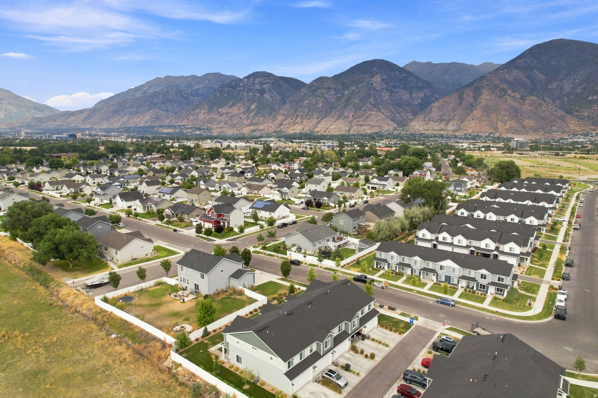 Residential neighborhood with a mix of single-family homes and townhomes, surrounded by open fields and distant mountains