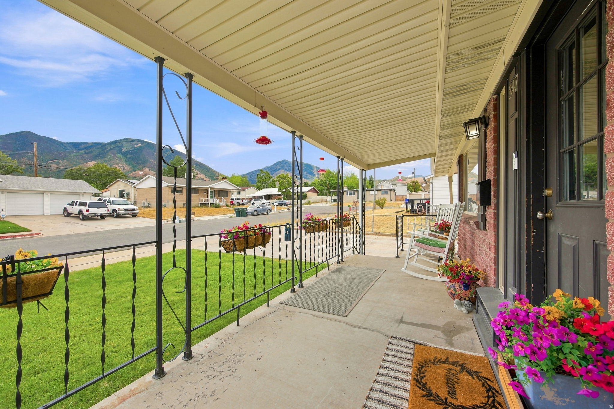 Covered front porch with concrete flooring, brick exterior, and decorative wrought iron railing
