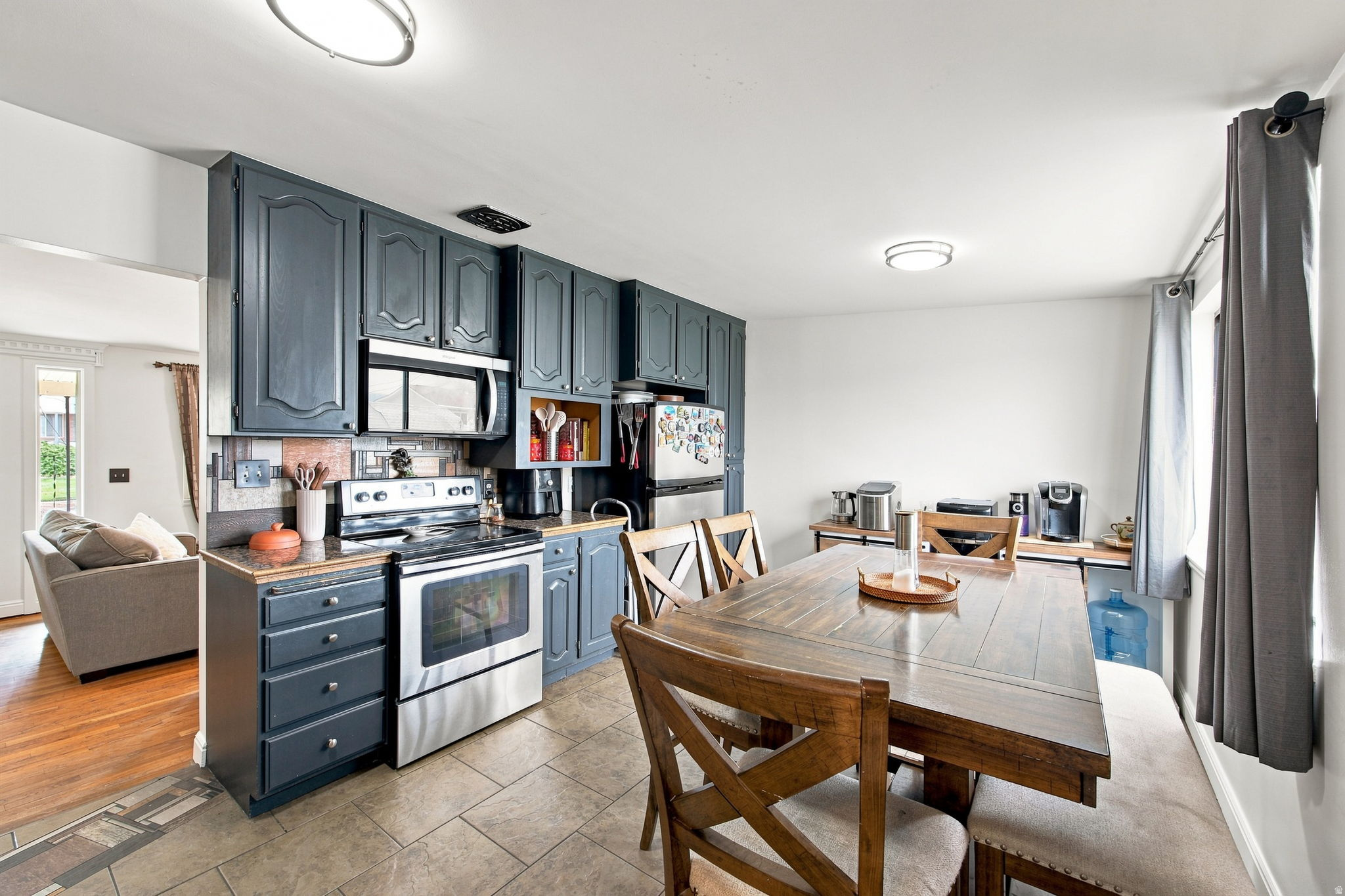 Kitchen with dark-painted cabinetry, stainless steel appliances, and a tiled backsplash