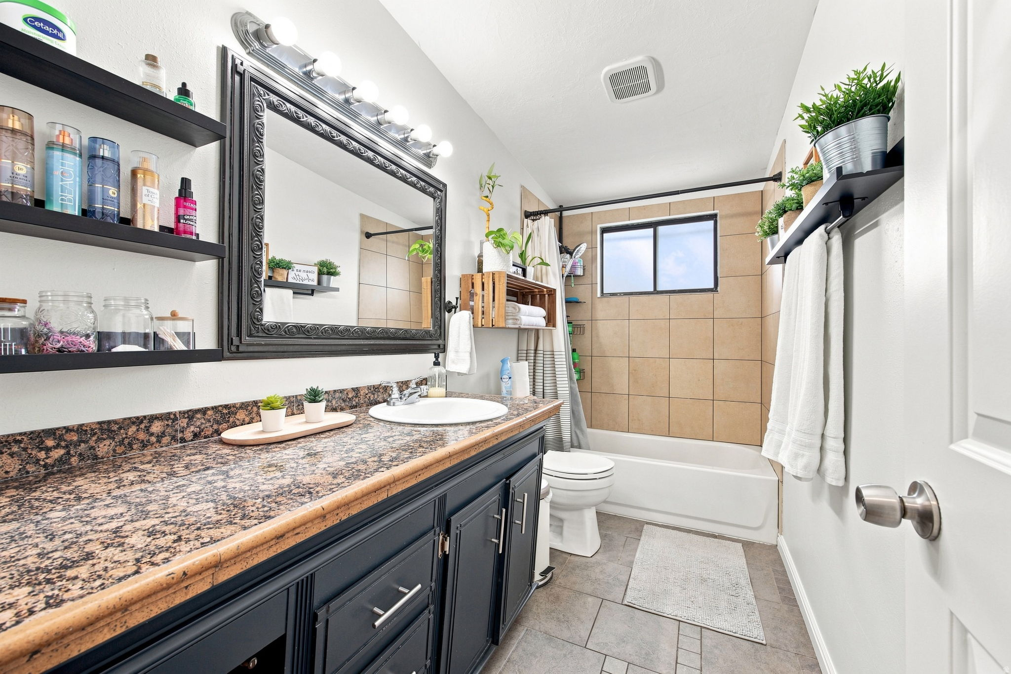 Bathroom featuring a dark wood vanity with a granite-style countertop, a framed mirror, and a white porcelain sink