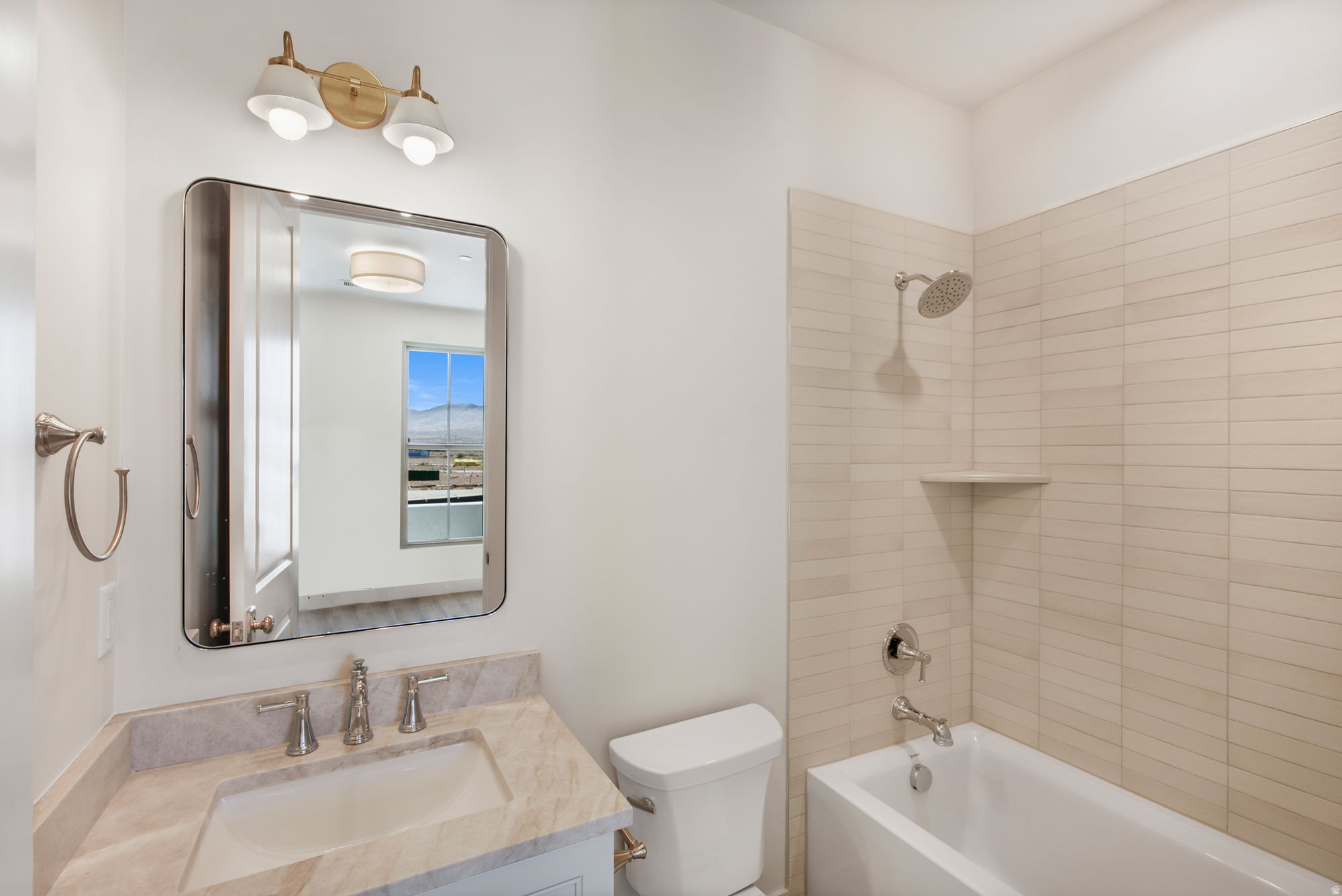 Bathroom featuring a vanity with an integrated sink, a rectangular mirror, and a built-in bathtub with tiled surrounds