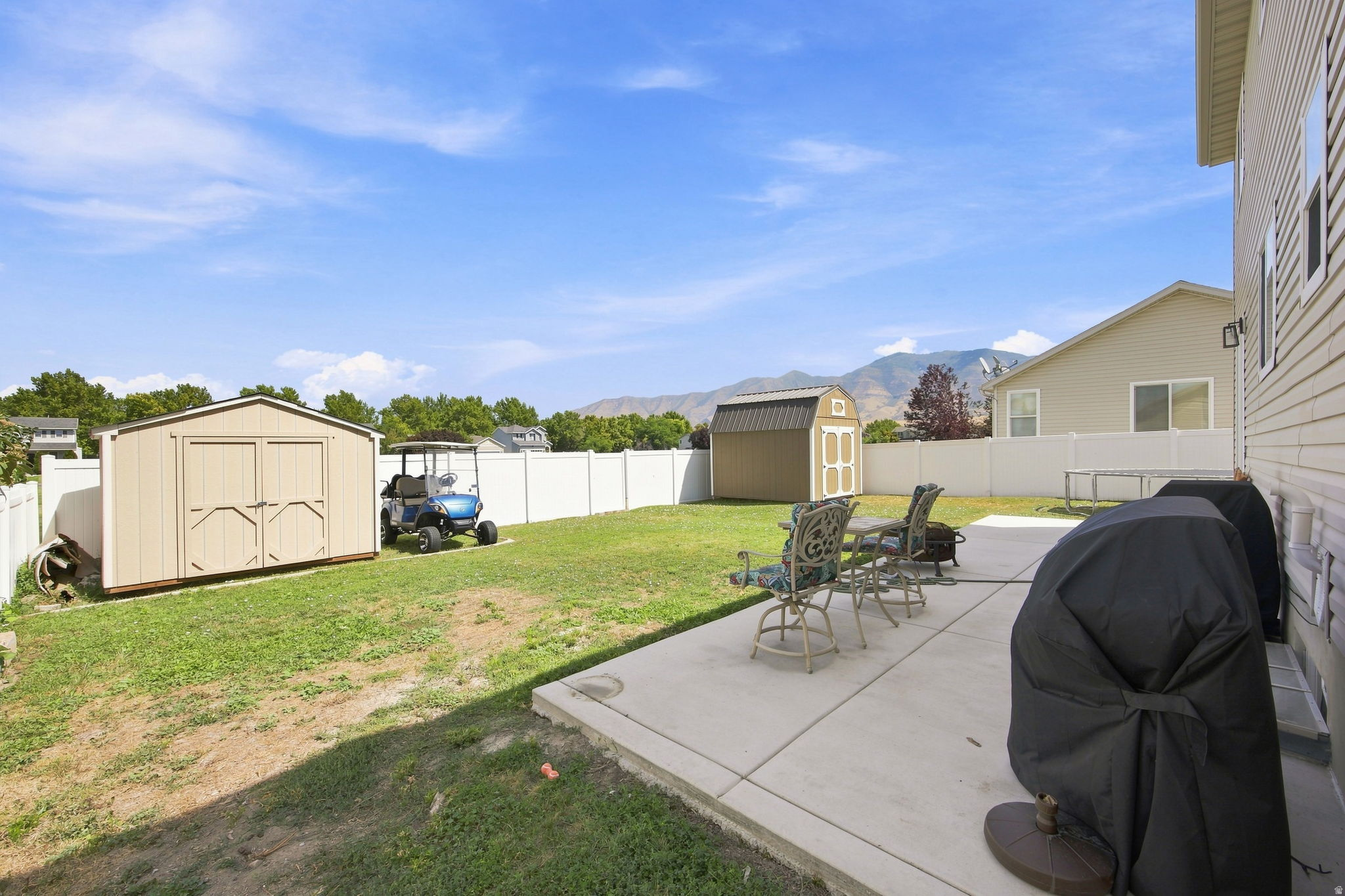 Expansive backyard featuring a concrete patio, a large storage shed, and a privacy fence