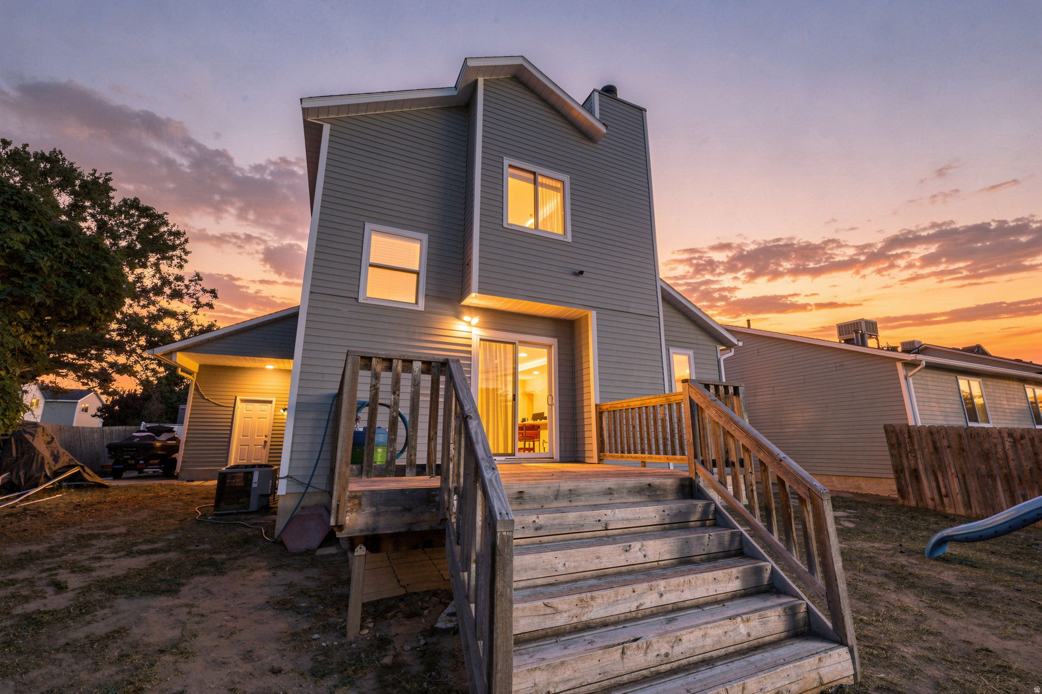 Multi-level home with horizontal siding, a two-story rear facade, and a wood deck with stairs