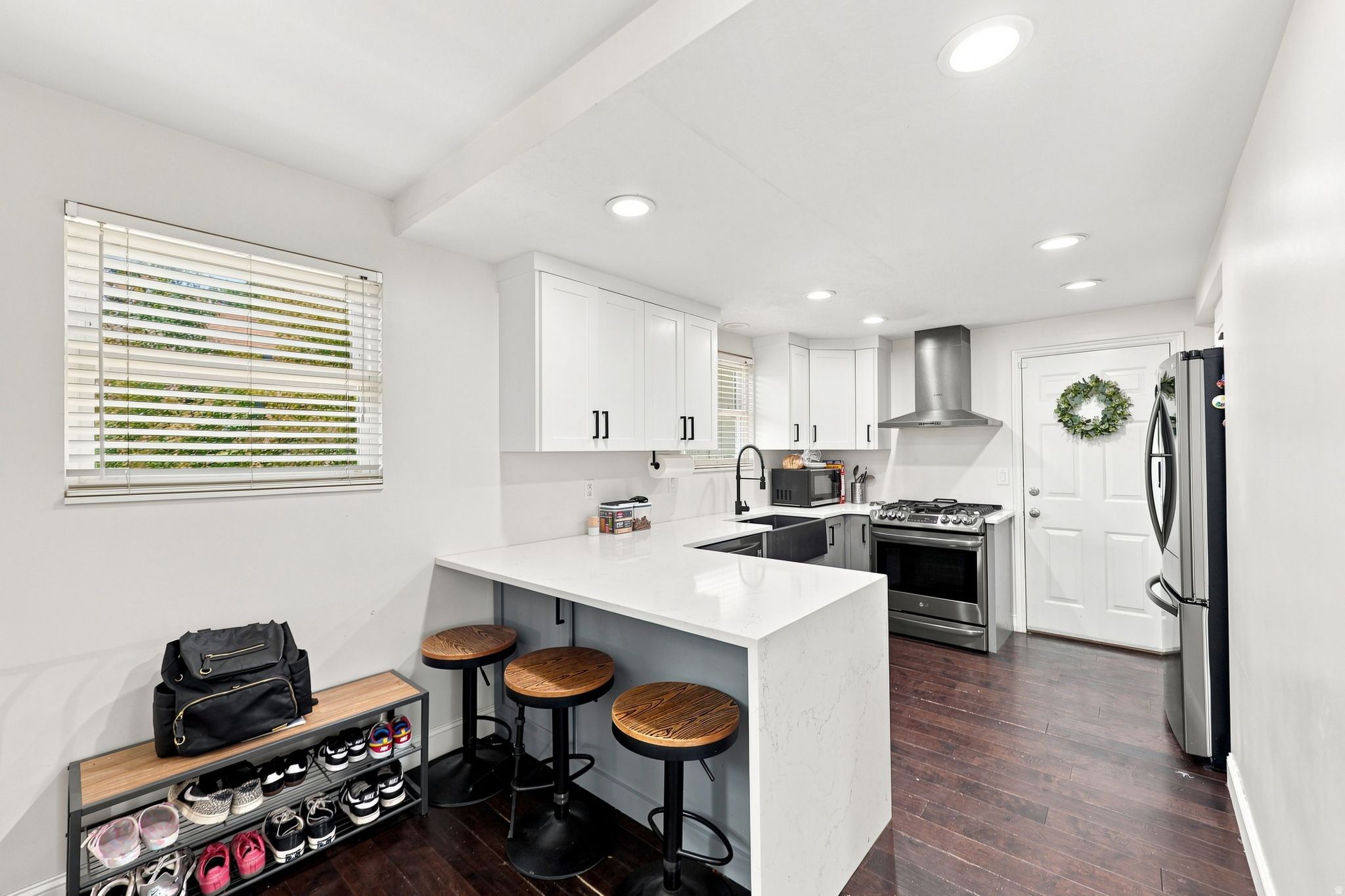 Modern kitchen featuring white cabinetry, stainless steel appliances, a white solid surface countertop, wood-finish flooring, and recessed lighting
