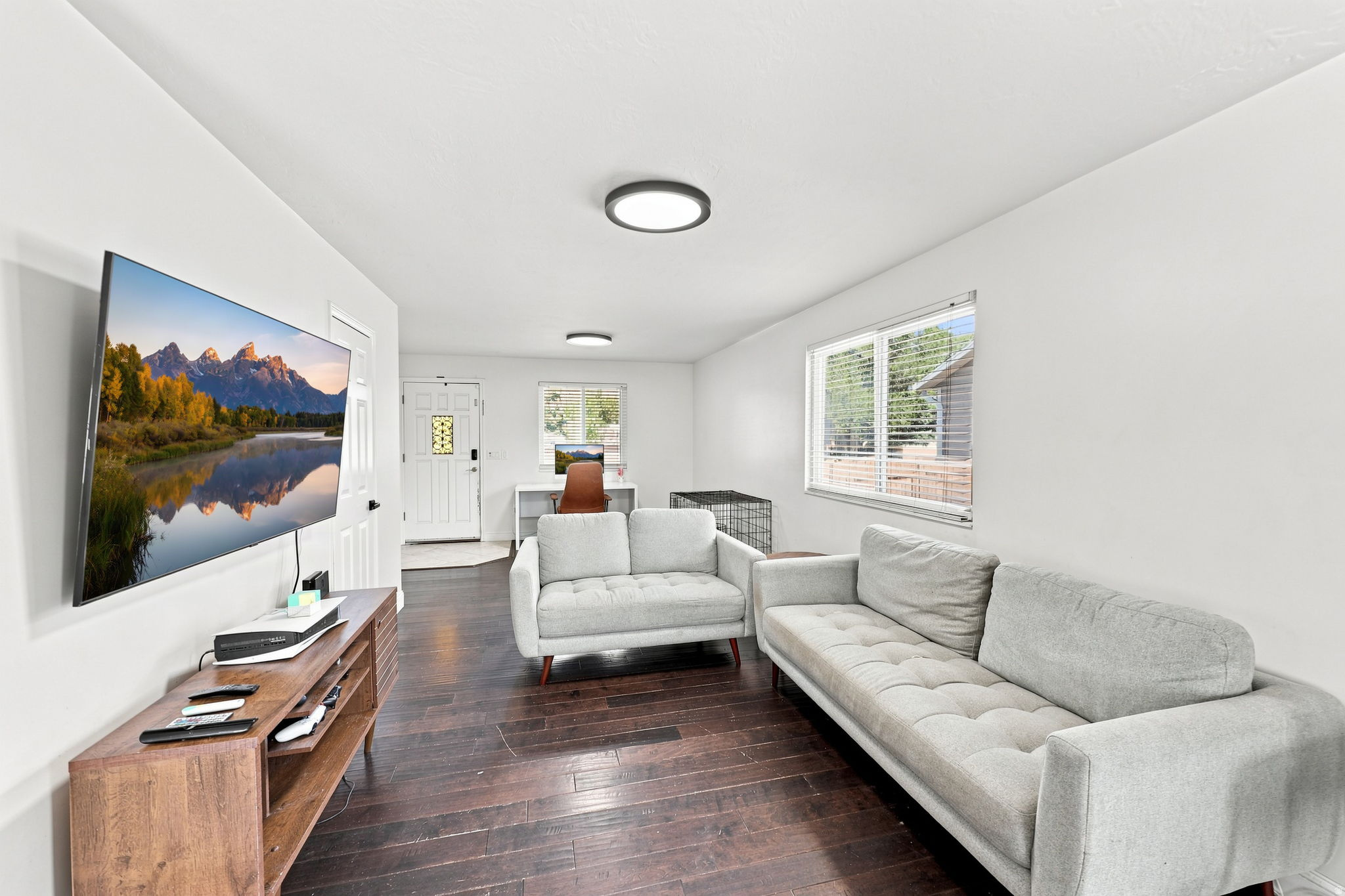 Spacious living area featuring dark wood-finish flooring and white walls