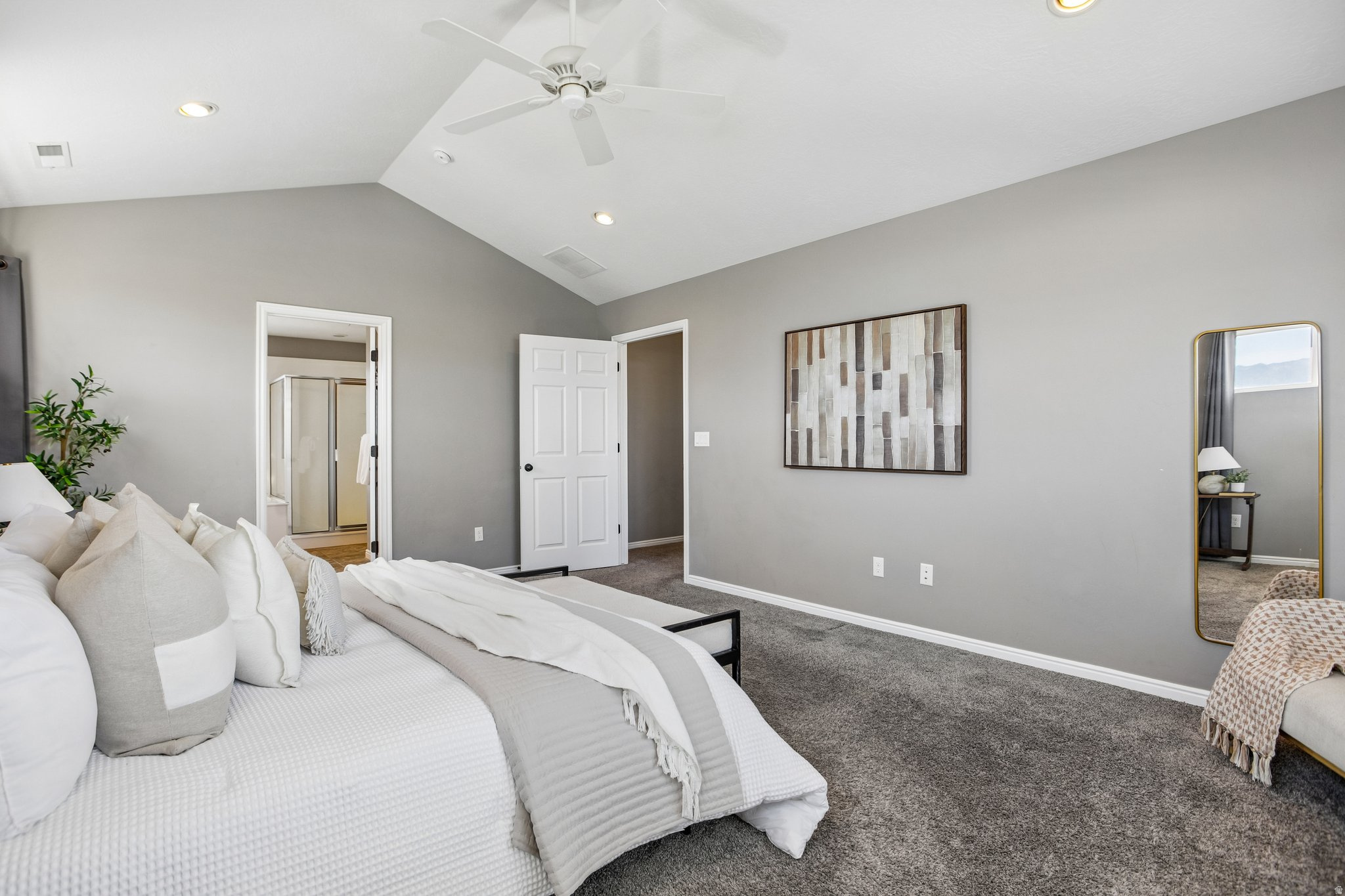 Vaulted ceilings with a ceiling fan and recessed lighting, plush carpeting, and a visible doorway to a bathroom featuring a glass-enclosed shower