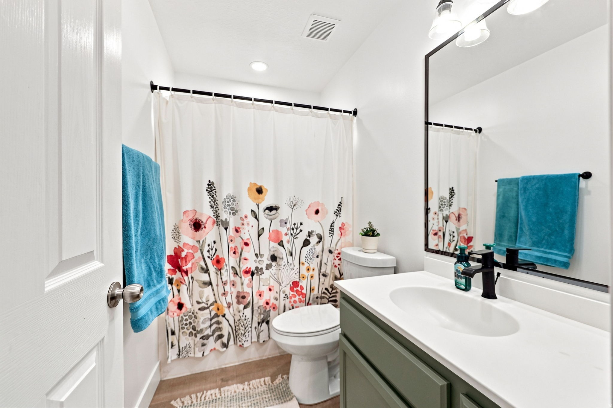 Bathroom featuring a single vanity with a white countertop, a black-framed mirror, and a toilet