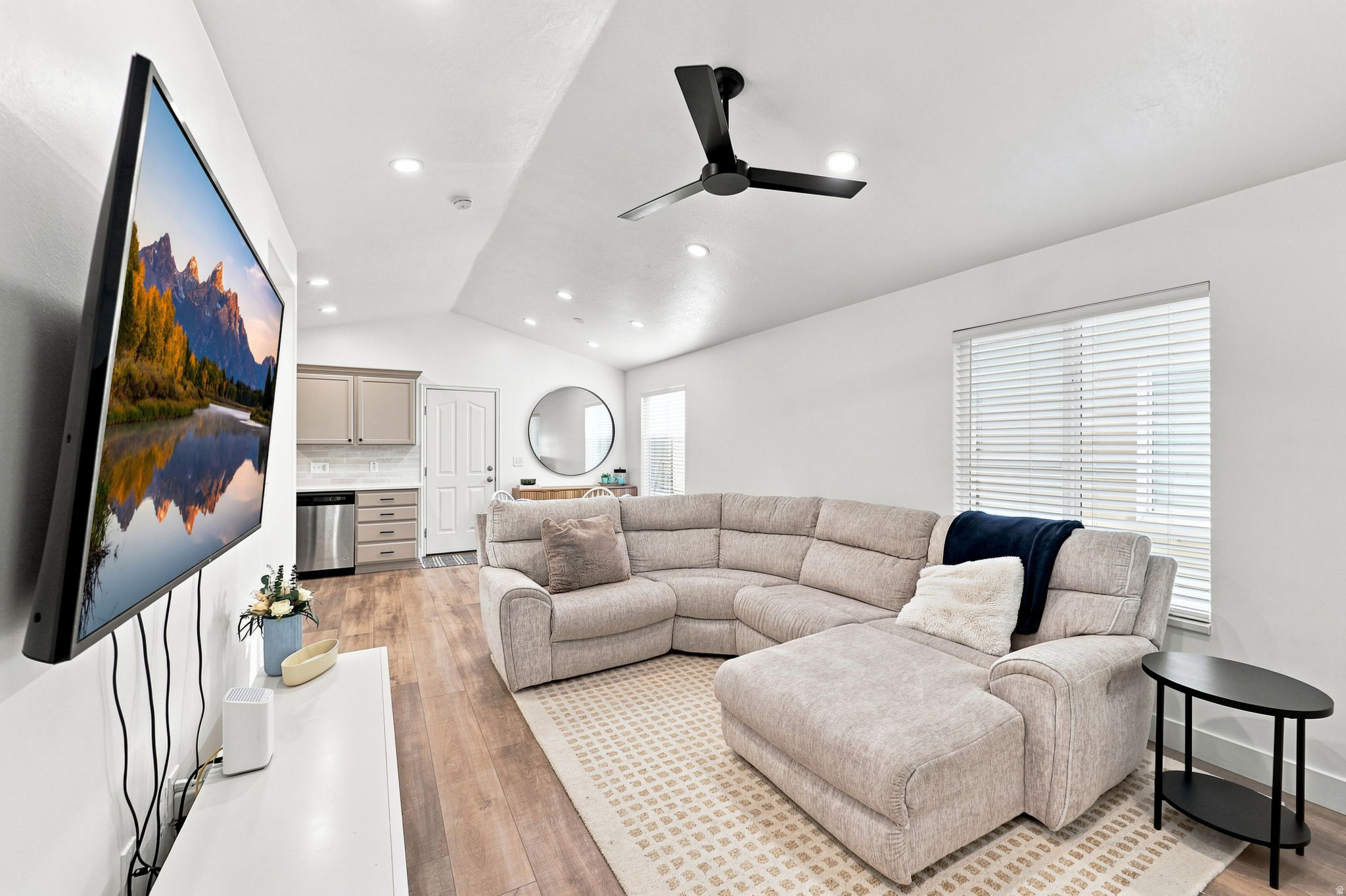 Vaulted ceiling with recessed lighting, wood-finish flooring, kitchen cabinetry, and a black ceiling fan