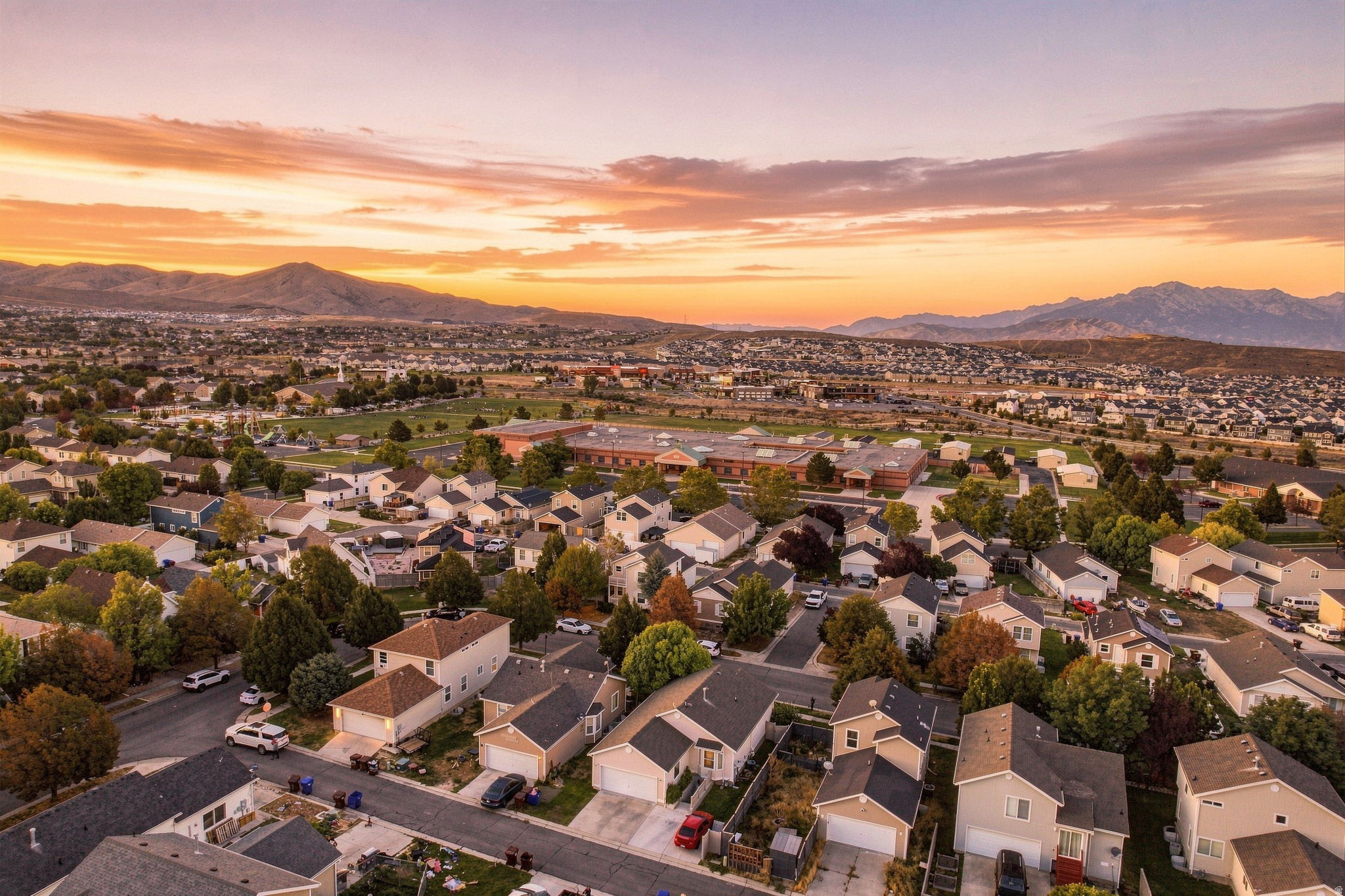 Residential neighborhood with varied architectural styles and mature trees, surrounded by distant mountains