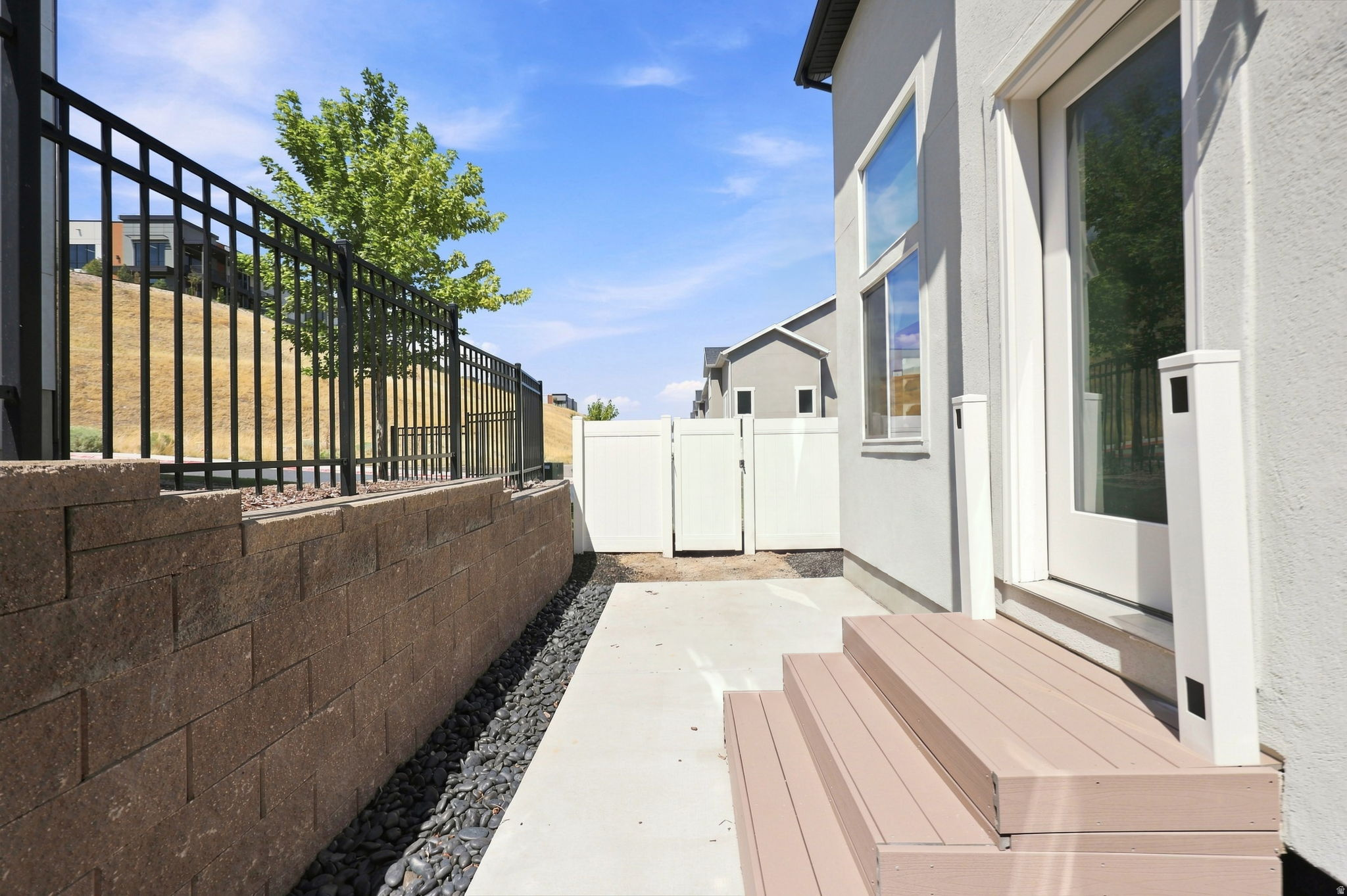 Walk-out patio with composite steps, concrete pathway, and a retaining wall