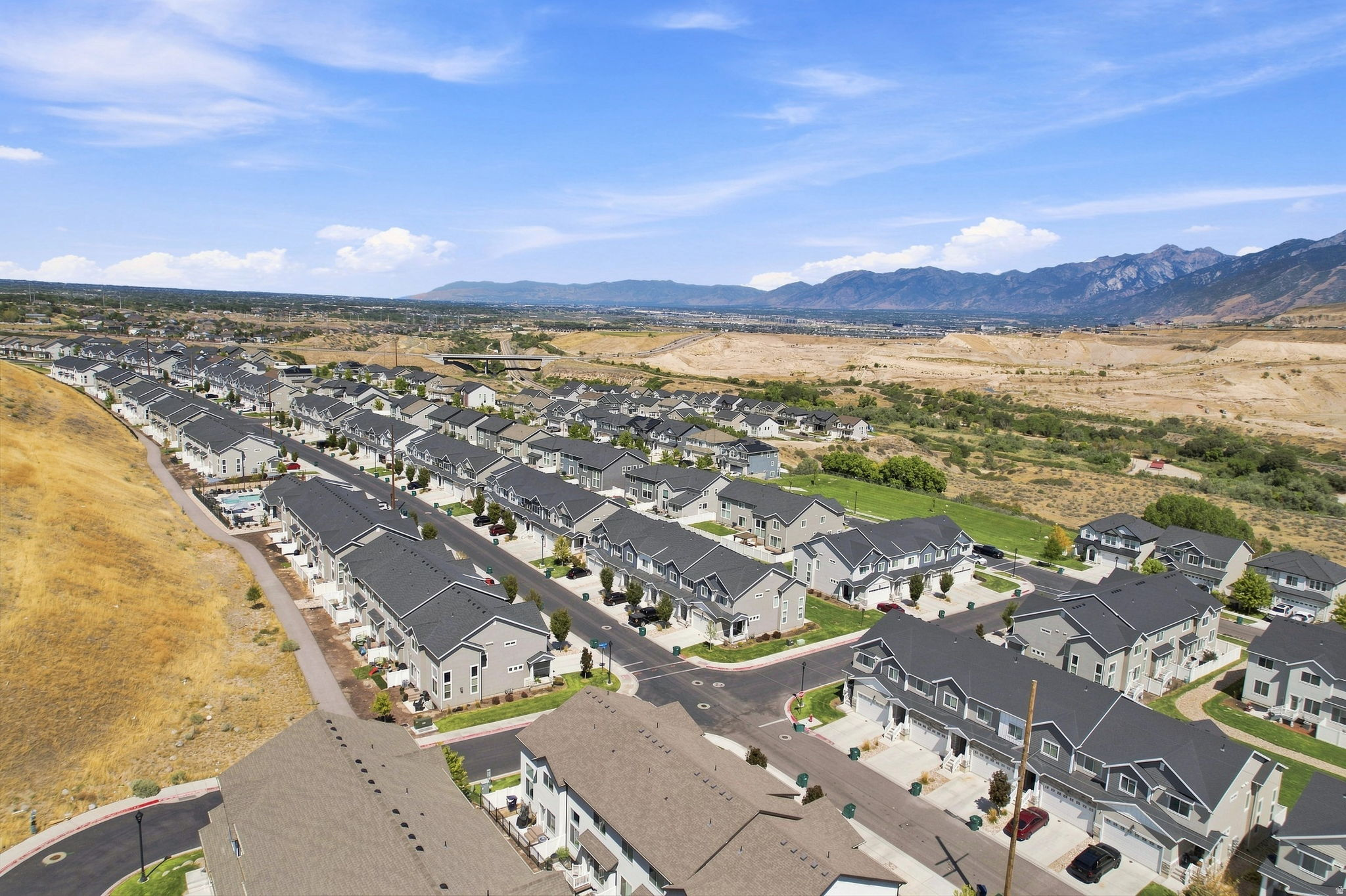 Residential development featuring multiple townhome-style residences, paved streets, and a mountainous backdrop