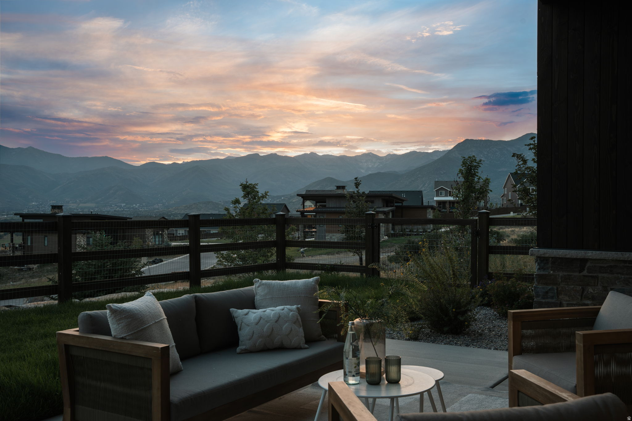 Outdoor patio with a concrete surface, bordered by a wooden fence, and a distant mountain range