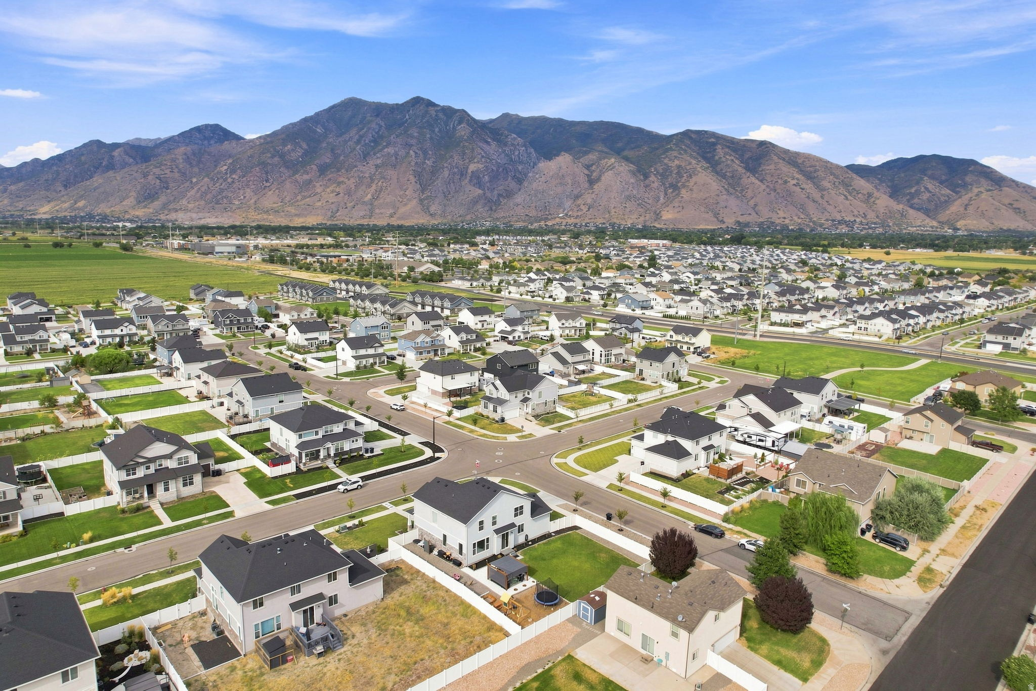 Expansive suburban neighborhood with mountain scenery, featuring a collection of two-story homes with dark roofs and light-colored exteriors