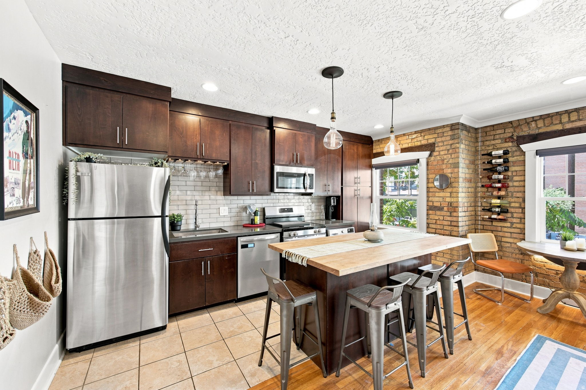 Kitchen featuring dark wood cabinetry, stainless steel appliances, tile backsplash, and a central island with a wood-finish countertop