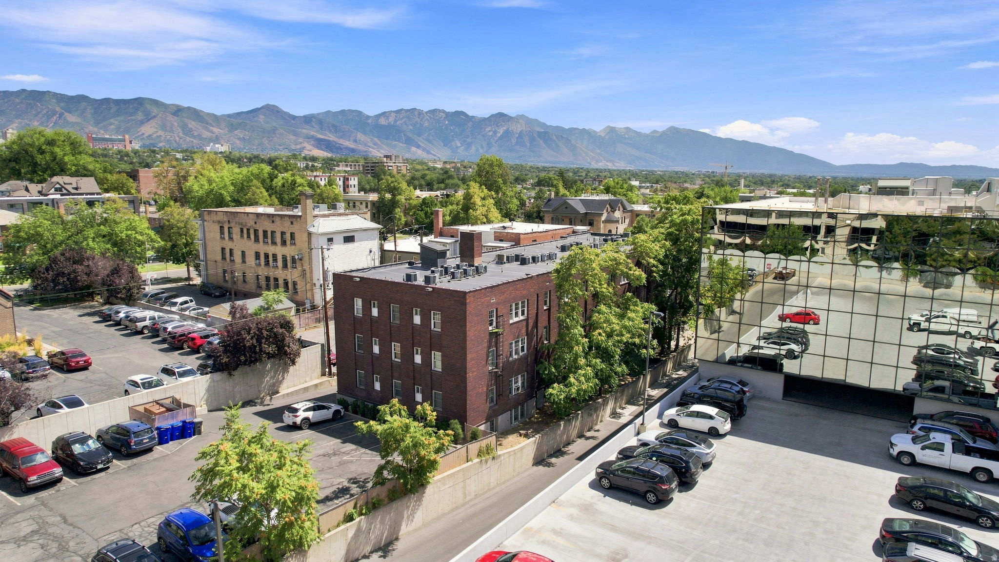 Mountain backdrop with expansive urban landscape, featuring multiple parking areas and commercial structures