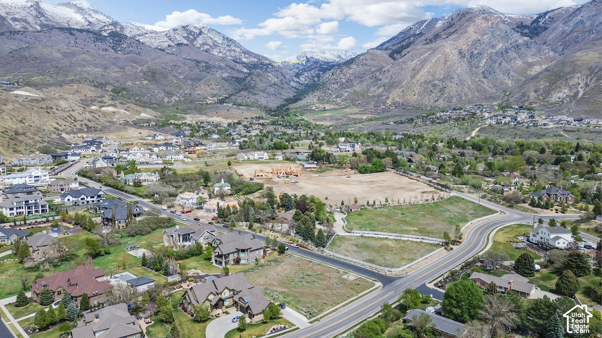Aerial view of Alpine homes and new construction beneath snow-dusted mountains.