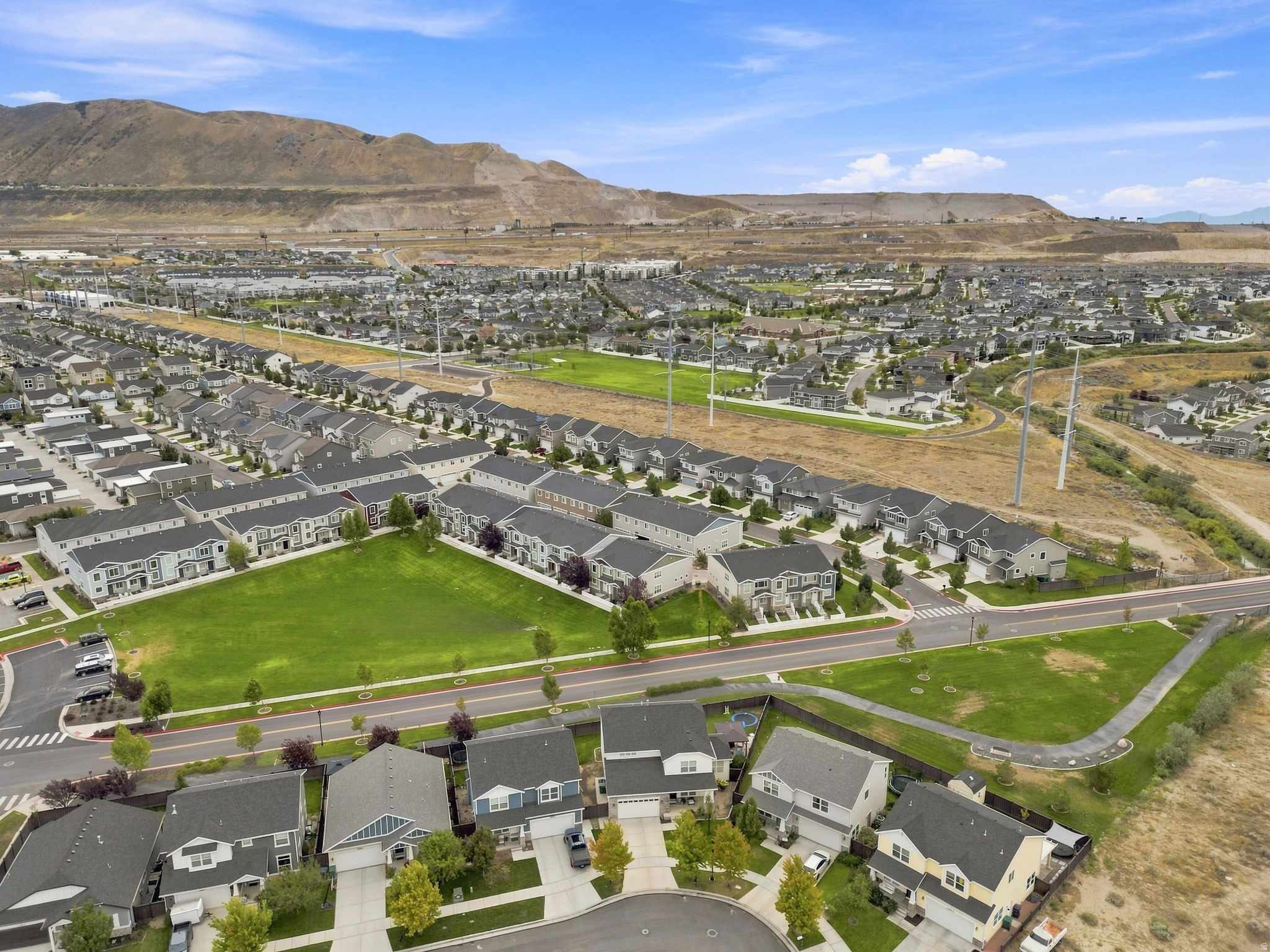 Residential neighborhood with a mountain backdrop, featuring single-family homes, townhomes, and green spaces