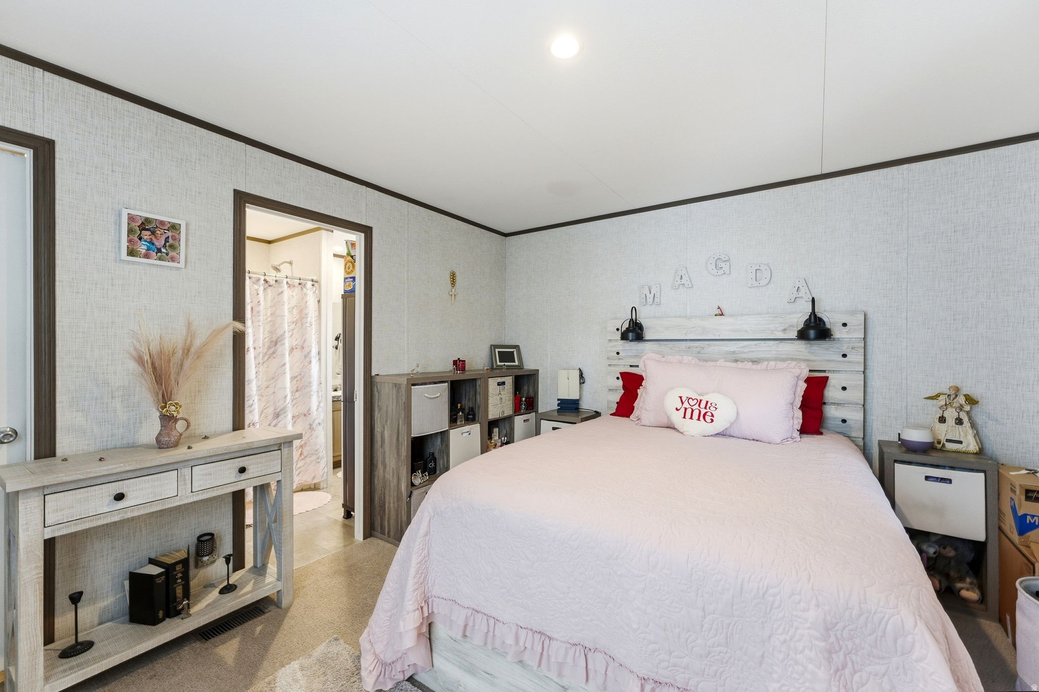 Recessed ceiling lighting, textured wall finishes, dark trim accents, wood-finish flooring, and an open doorway to an adjoining bathroom