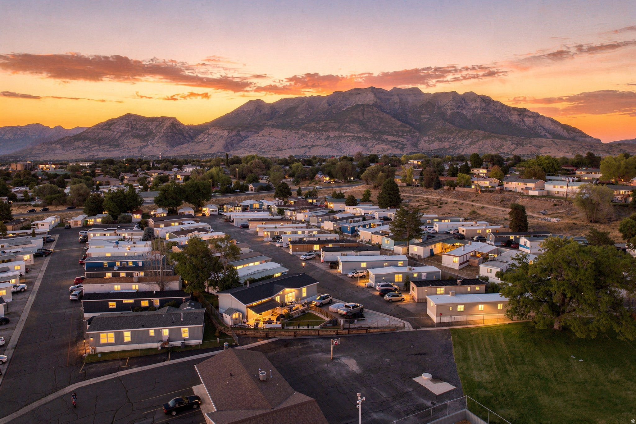 Expansive mountain backdrop with a community setting featuring multiple residences and paved roadways