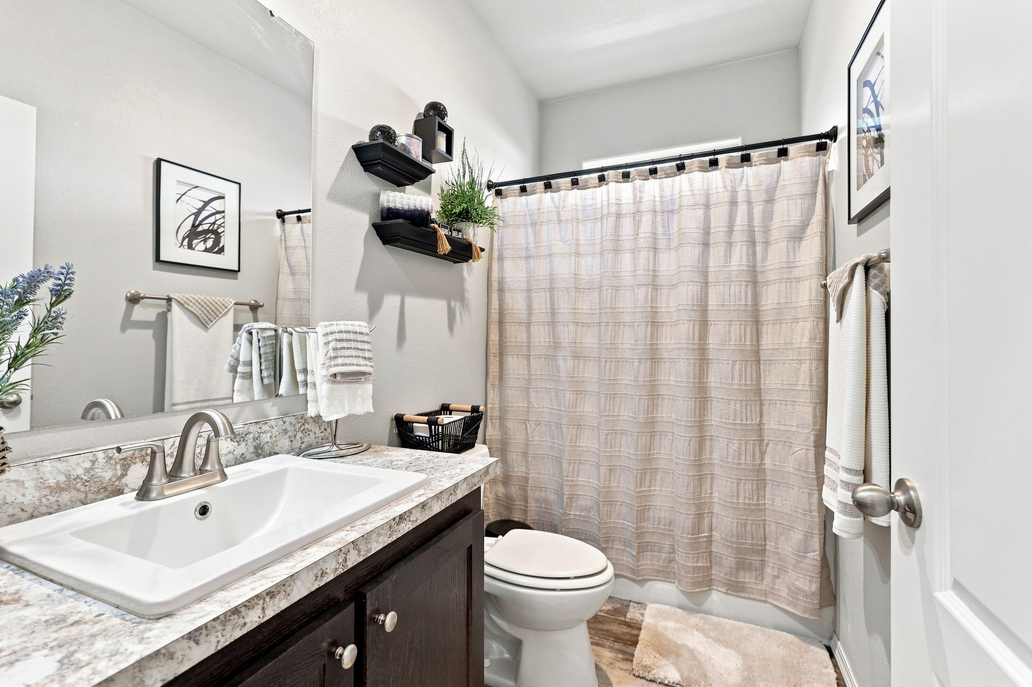 Bathroom featuring a vanity with dark wood-finish cabinetry, white integrated sink, and a framed mirror