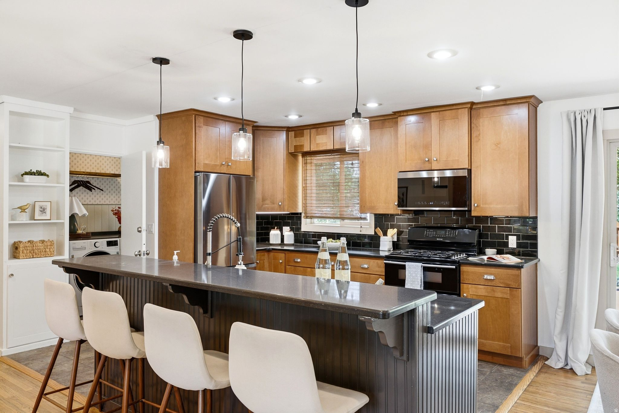 Kitchen featuring wood cabinetry, stainless steel appliances, a tile backsplash, recessed lighting, and a breakfast bar with pendant lighting