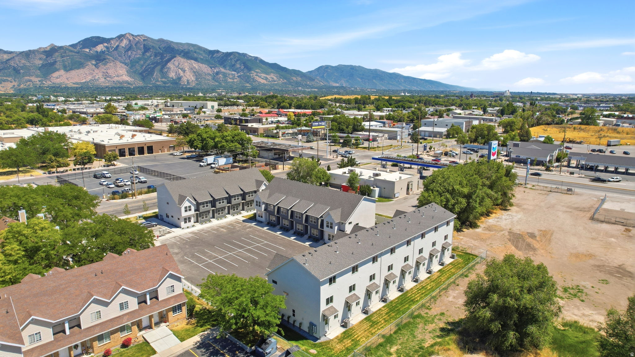 Townhome-style residences with multiple units, ample surface parking, and a backdrop of mountain scenery