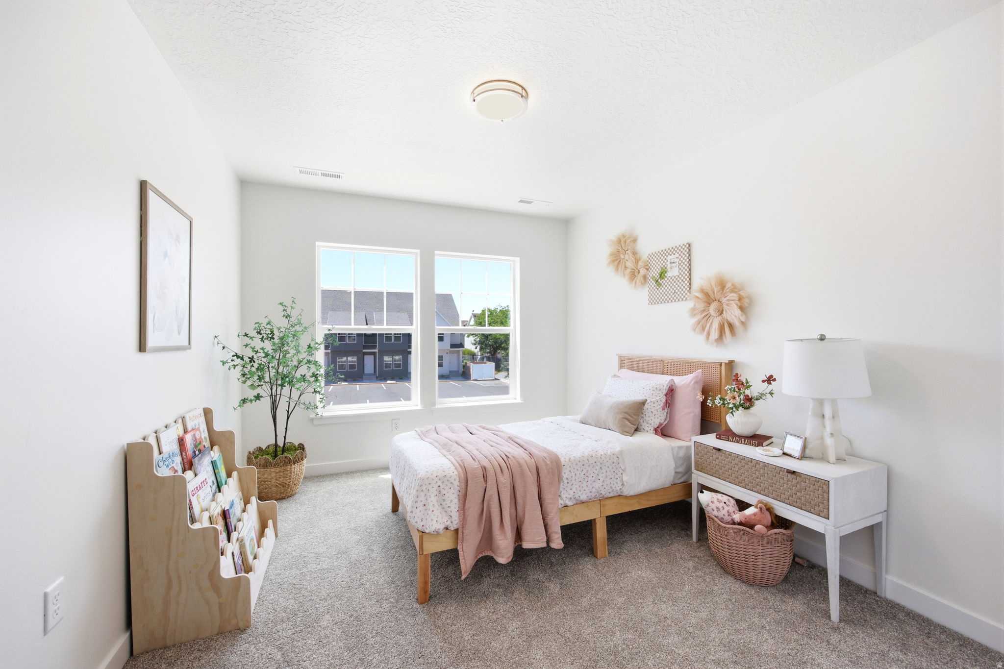 Bright bedroom featuring two large windows, white walls, textured carpeting, and a flush mount ceiling light fixture