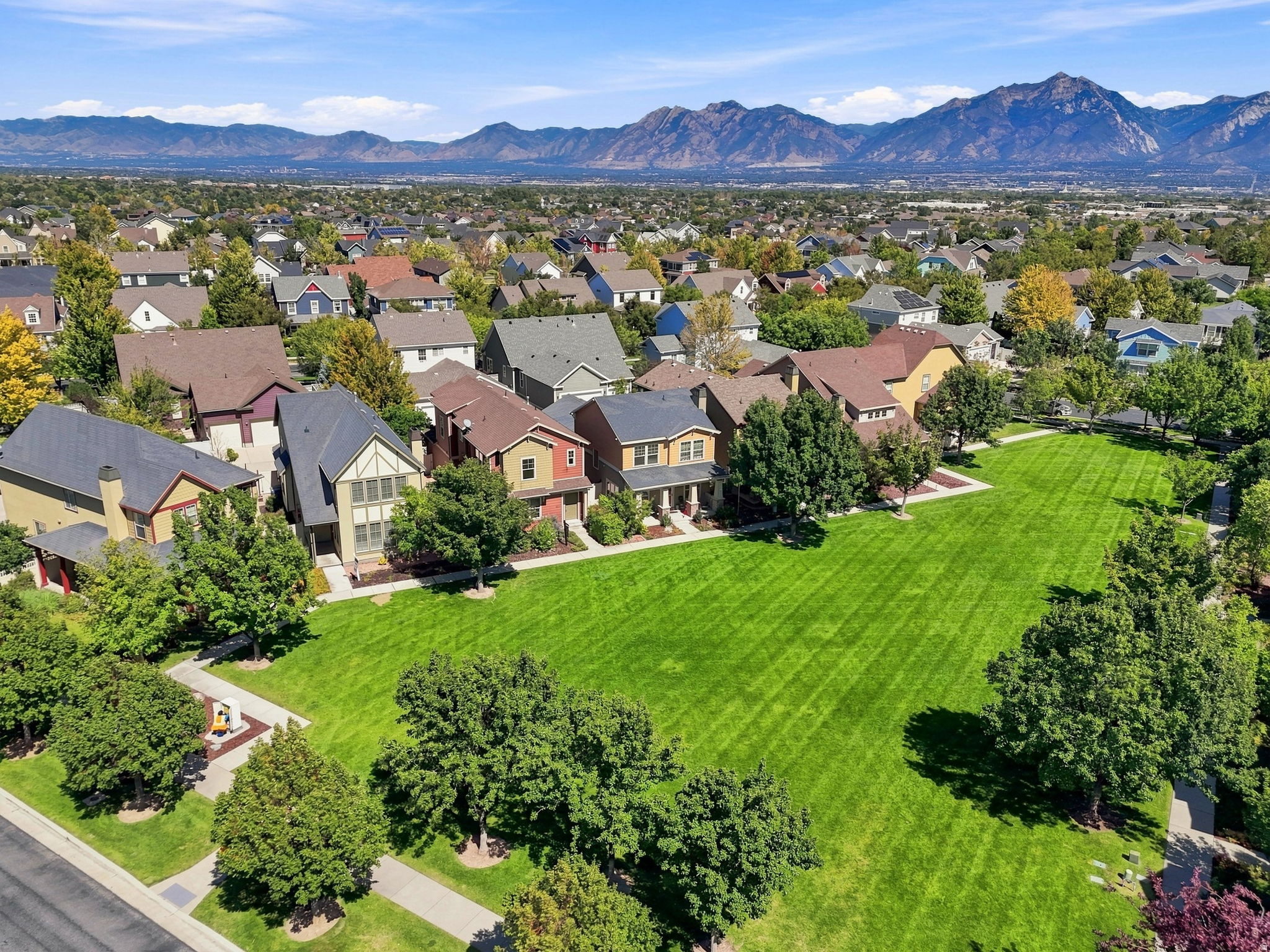Expansive green space featuring mature trees and mountain backdrop