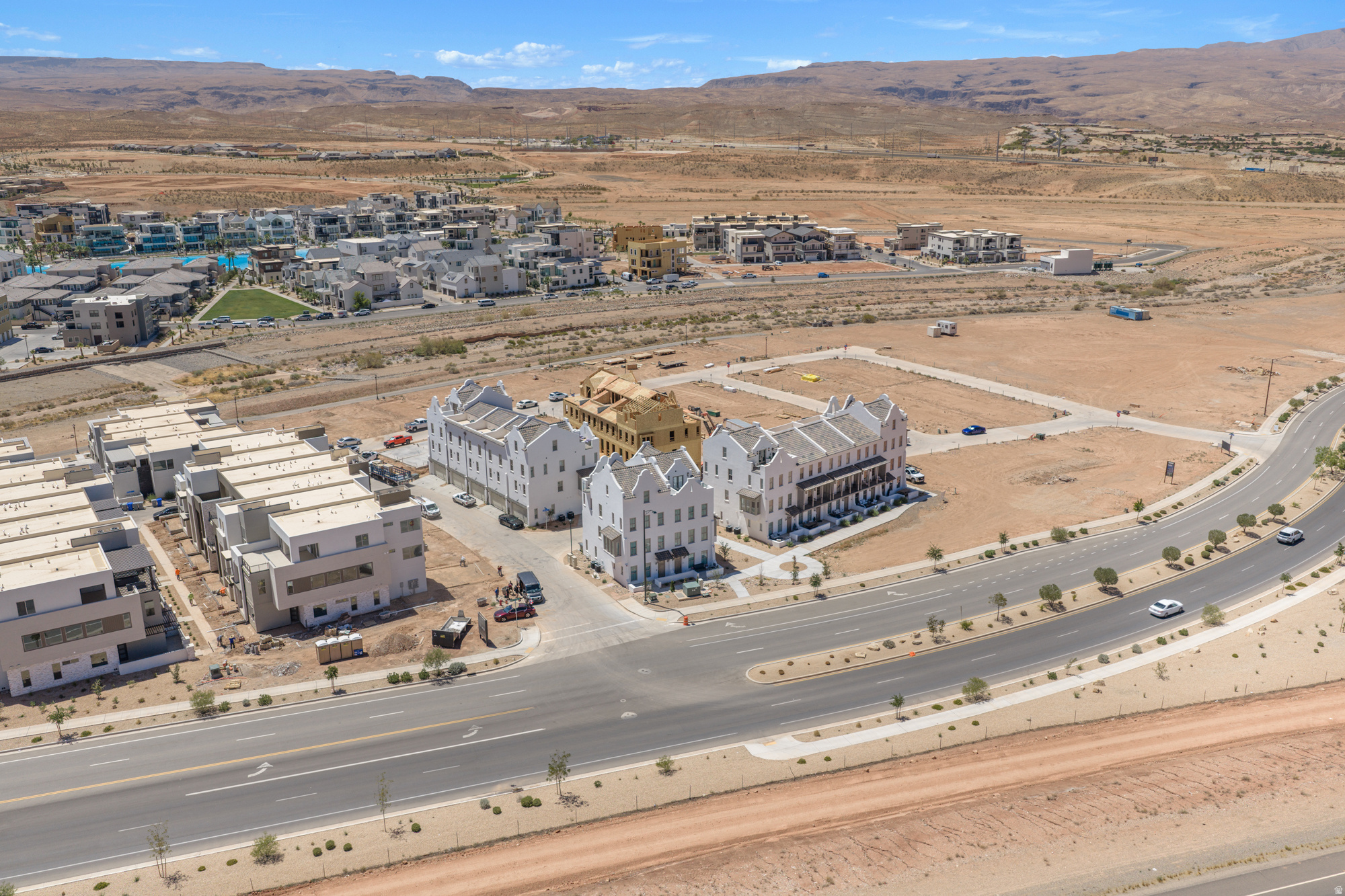 Aerial perspective of a developing community featuring diverse architectural styles, paved roadways, and surrounding desert landscape