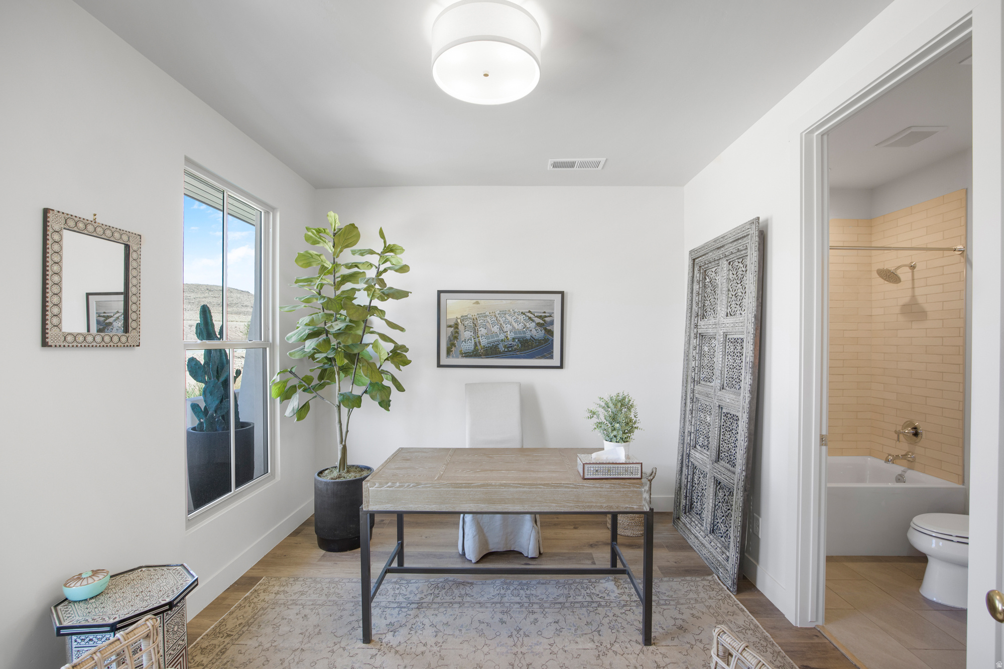 Well-lit interior space featuring wood-finish flooring, a contemporary flush mount ceiling light, and a window with a mountain backdrop