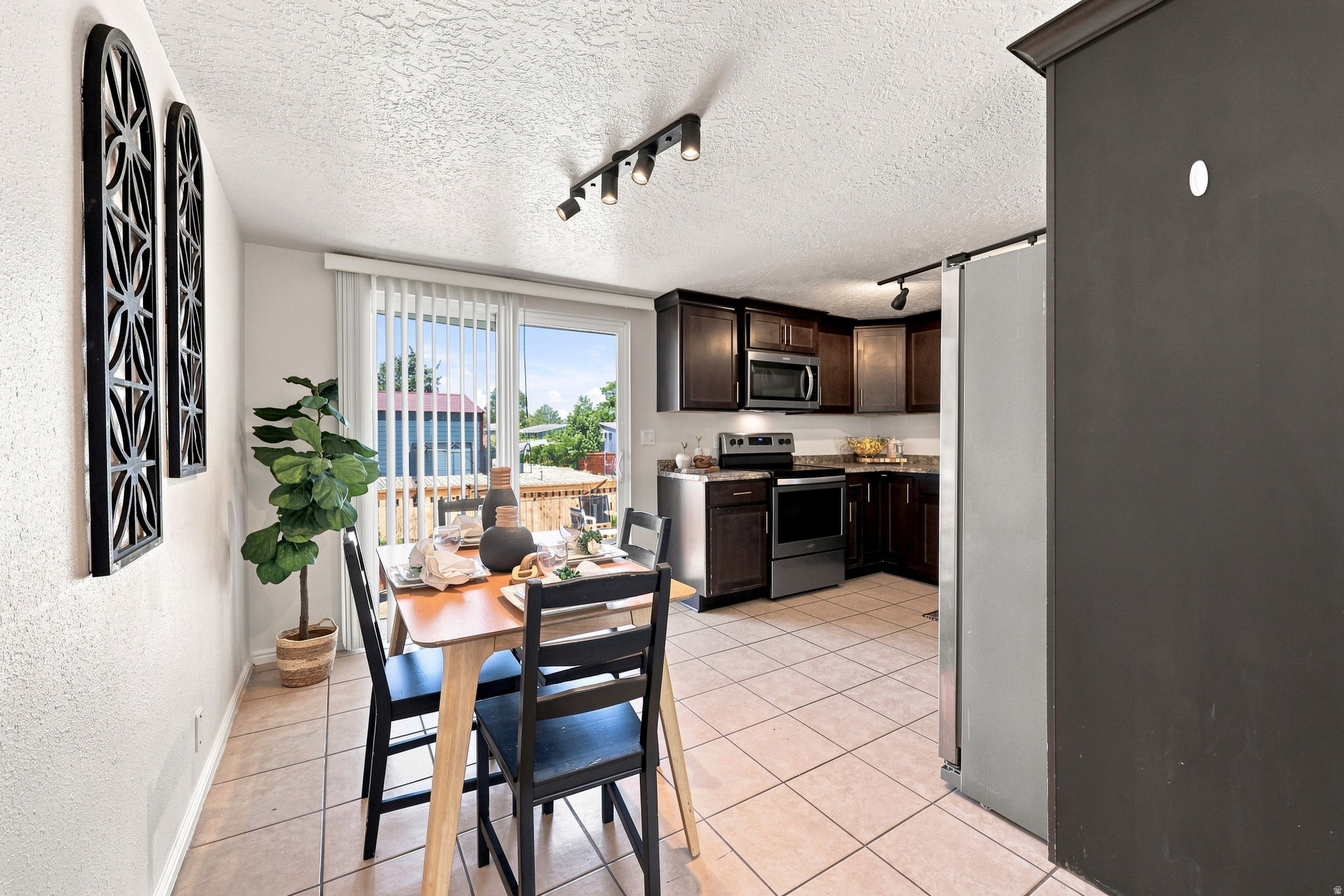 Kitchen featuring dark wood cabinetry, stainless steel appliances, and a tile floor
