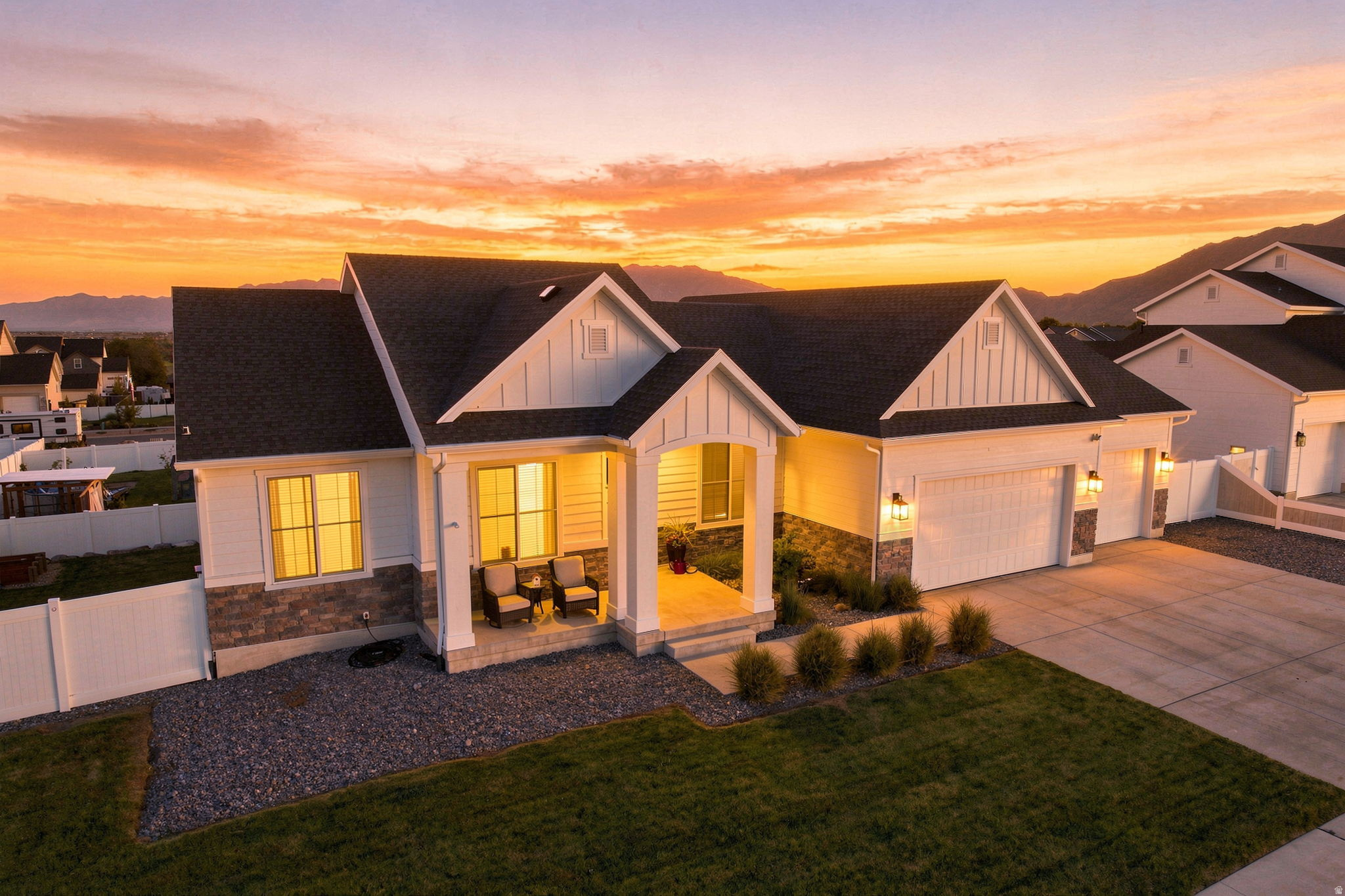 Contemporary ranch-style residence featuring a covered front porch, a two-car garage with carriage-style doors, and a stone and siding exterior