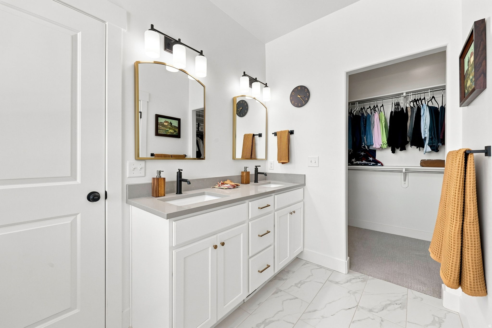 Primary bathroom featuring a dual-sink vanity with white cabinetry, quartz countertop, and brushed brass hardware