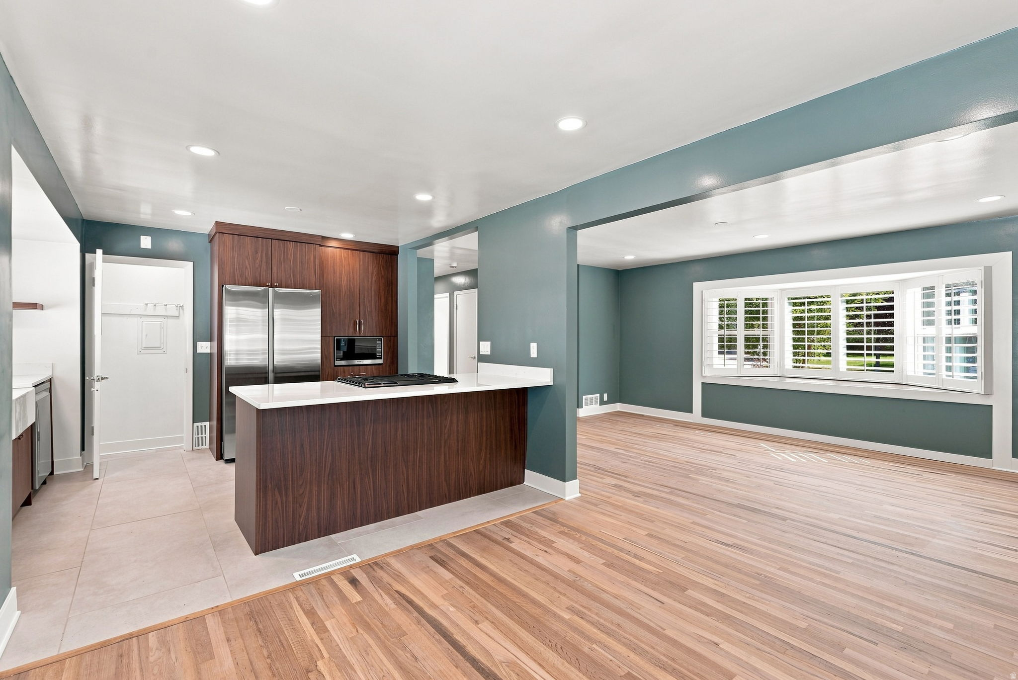 Wood-finish flooring, recessed lighting, and a kitchen island with a cooktop