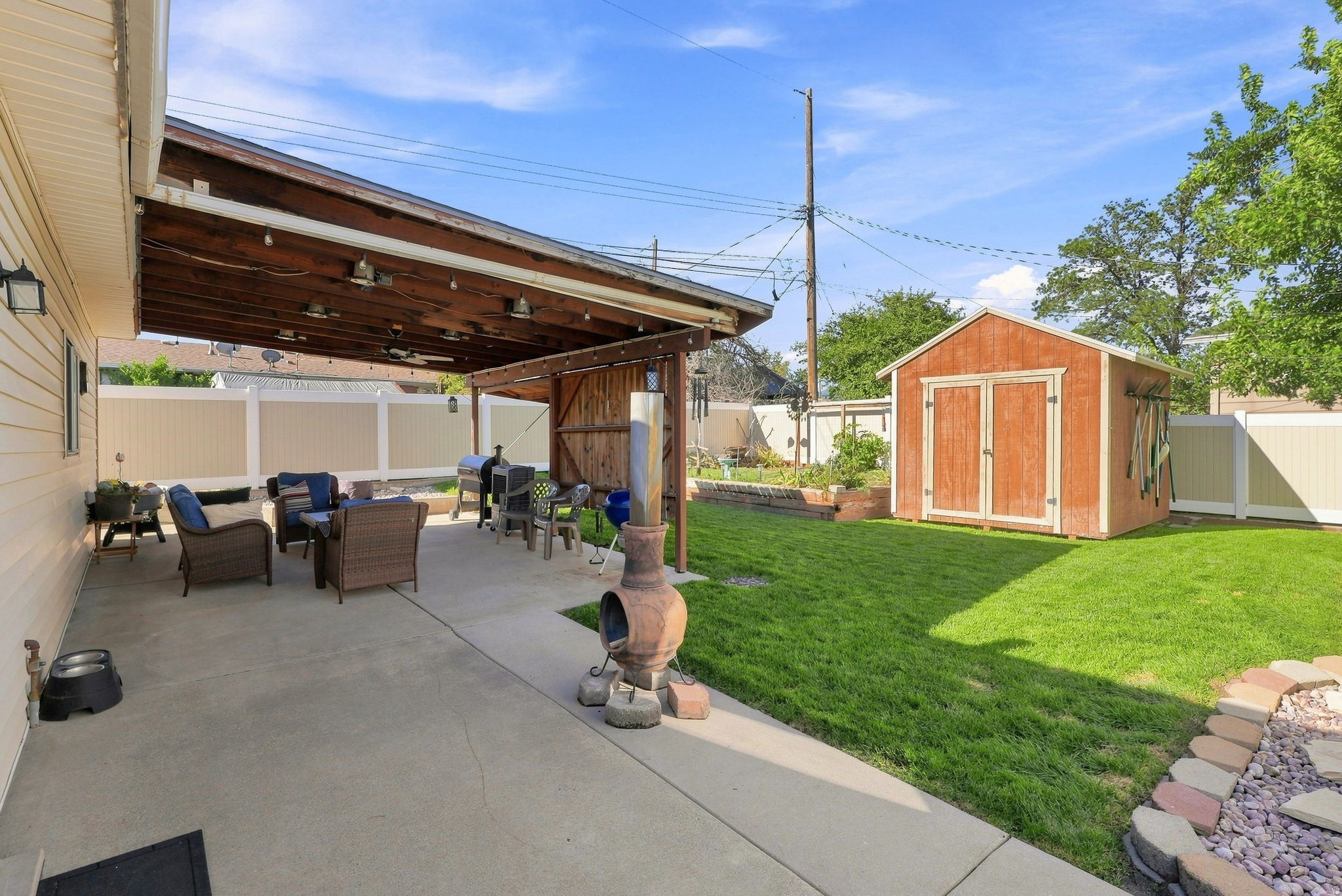 Expansive concrete patio with a wood-covered pergola and string lighting