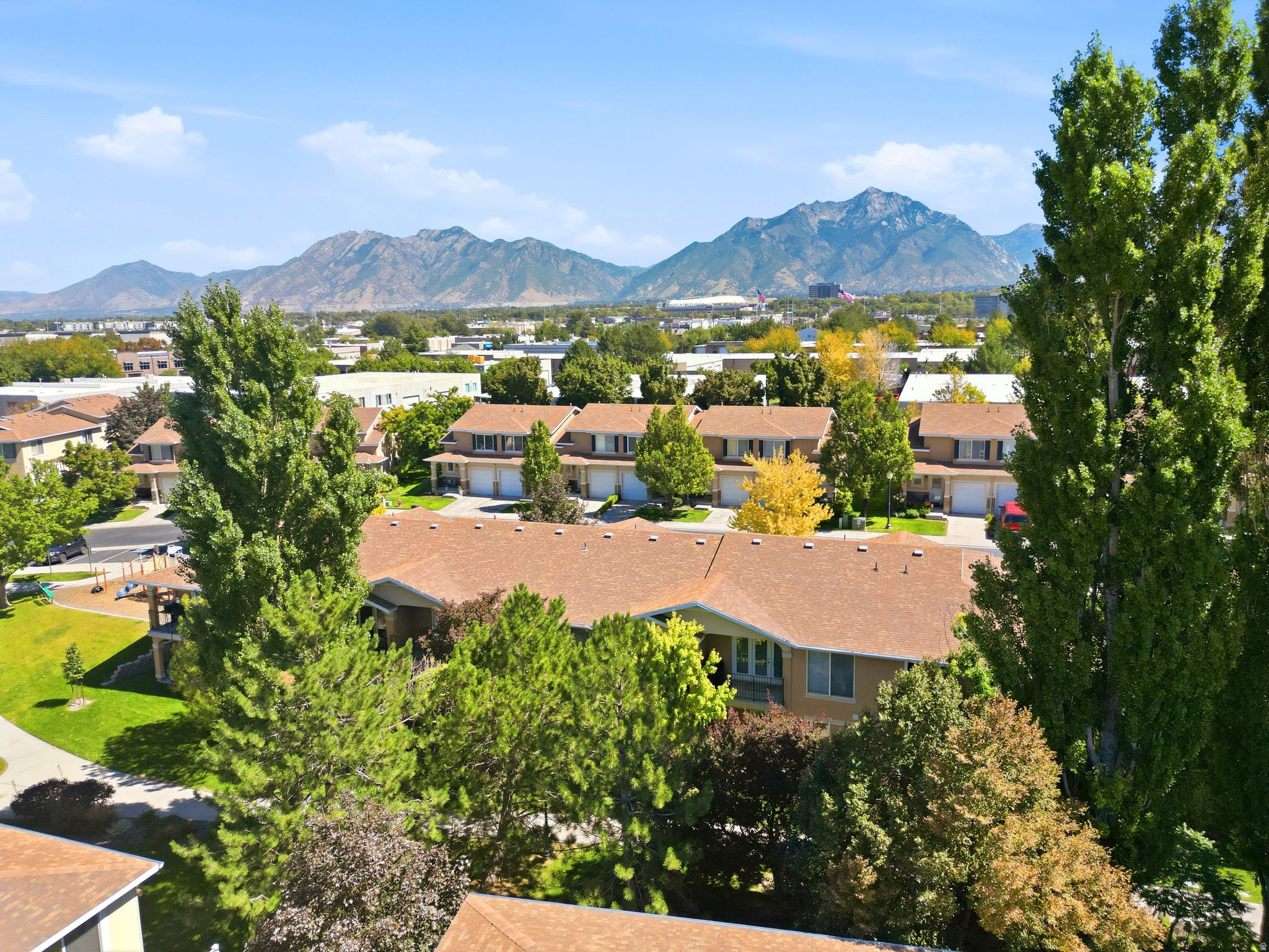 Community setting with townhomes, mature trees, and mountainous background