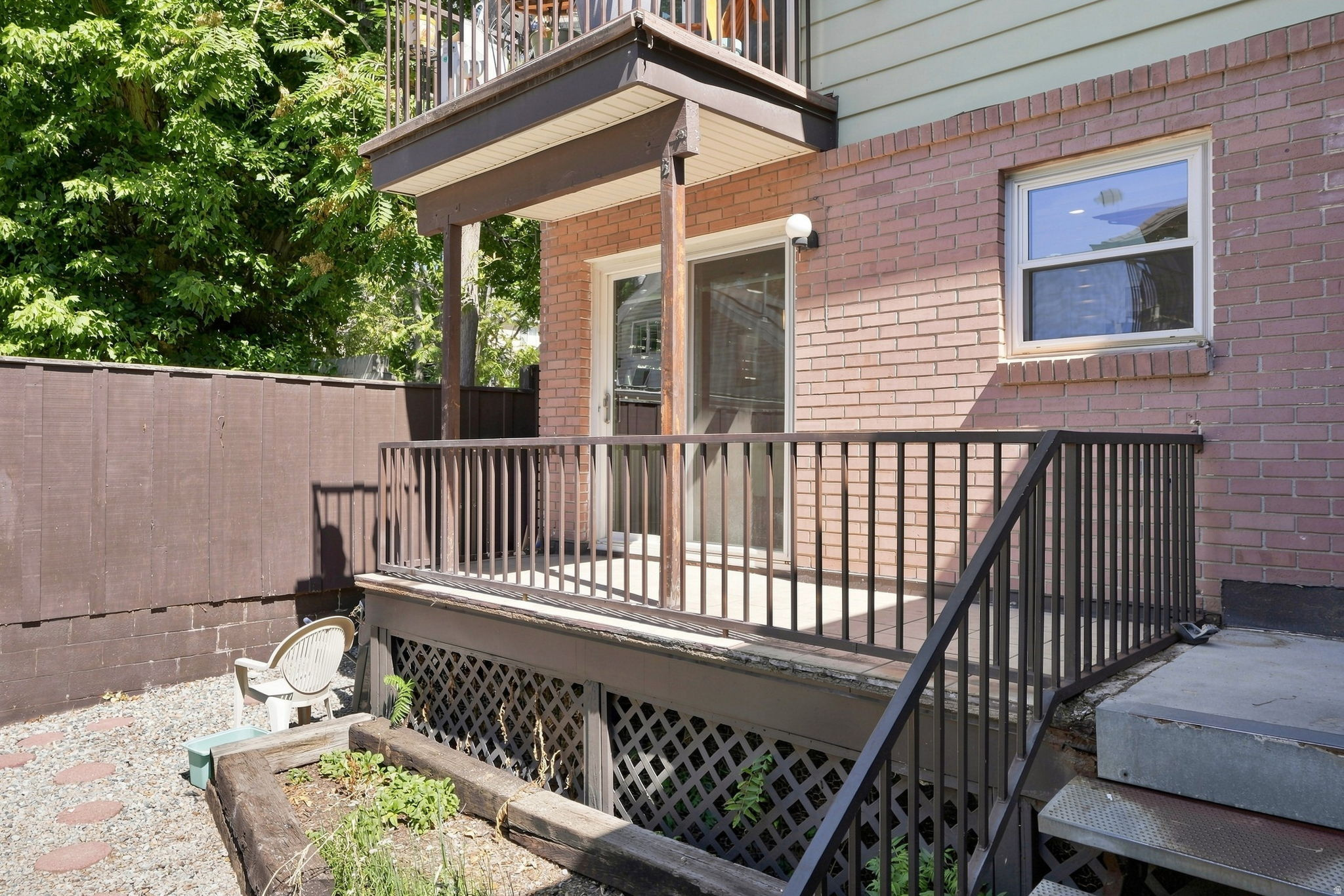 Lower-level patio with brick exterior and privacy fencing