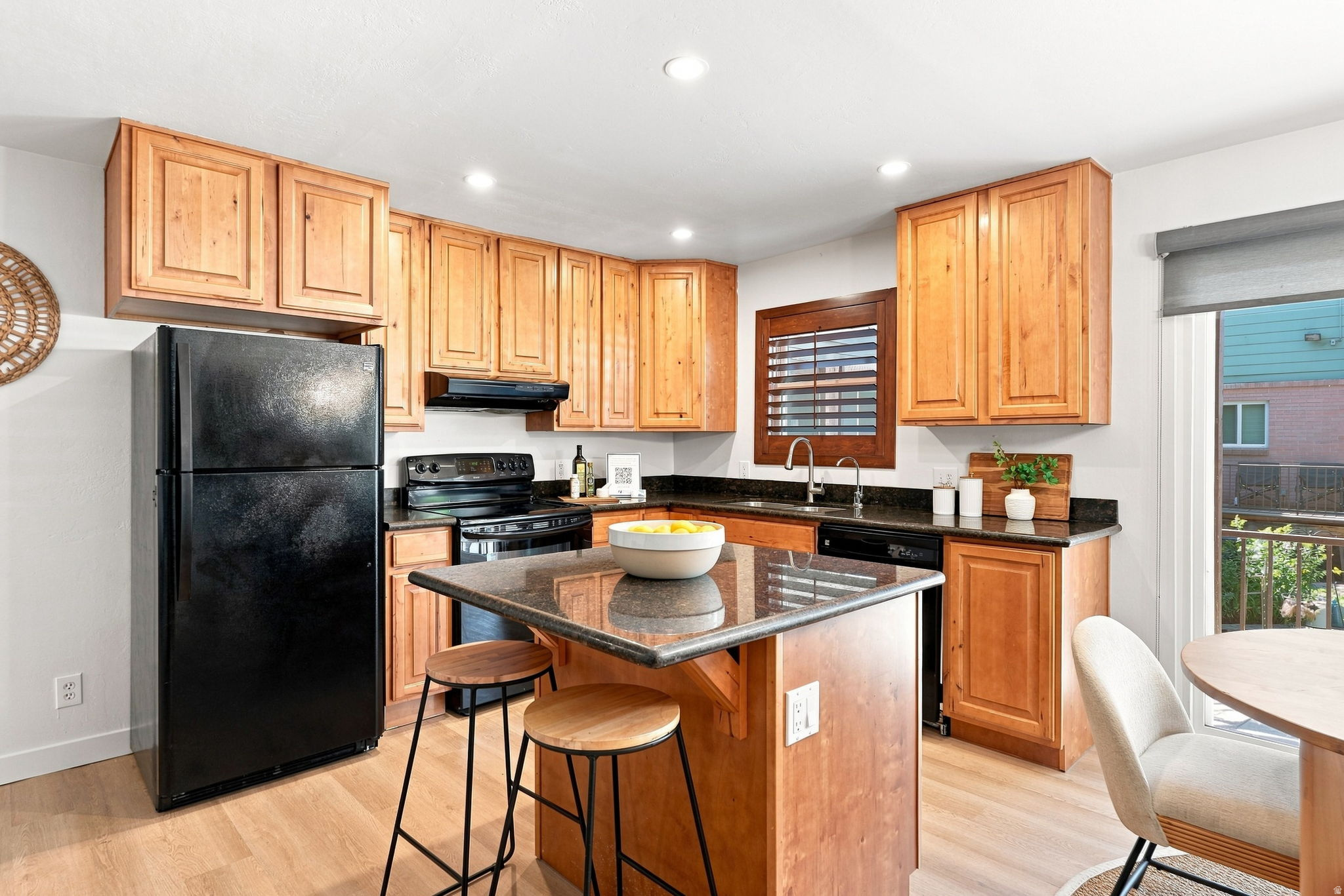 Kitchen featuring wood-finish cabinetry, black appliances, granite countertops, and recessed lighting