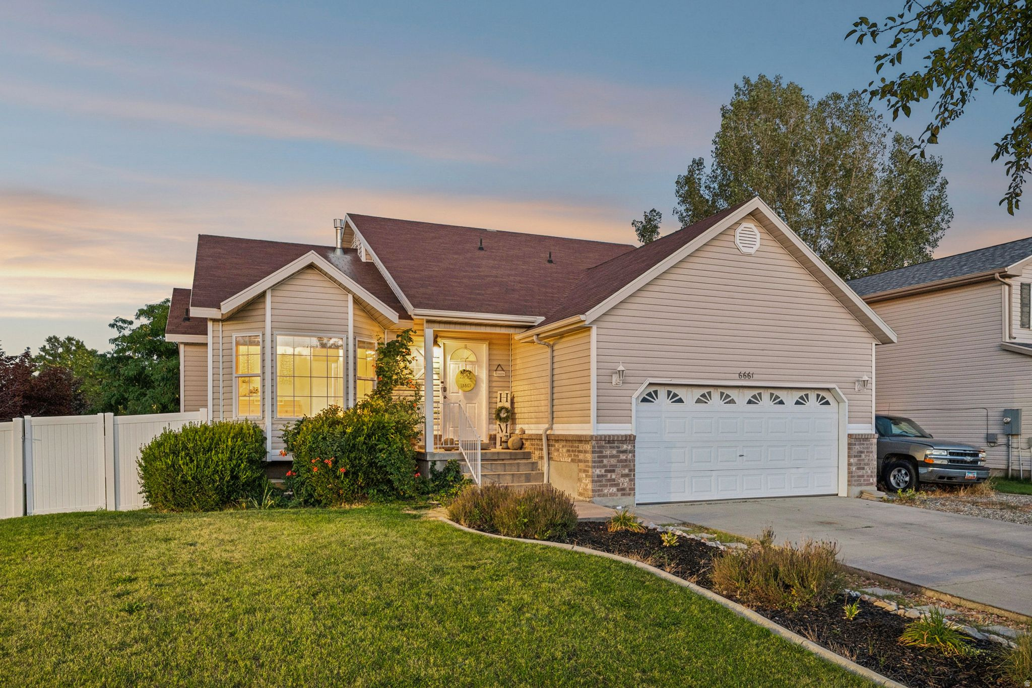 Siding exterior with brick accents, bay window, attached garage, and a fenced yard