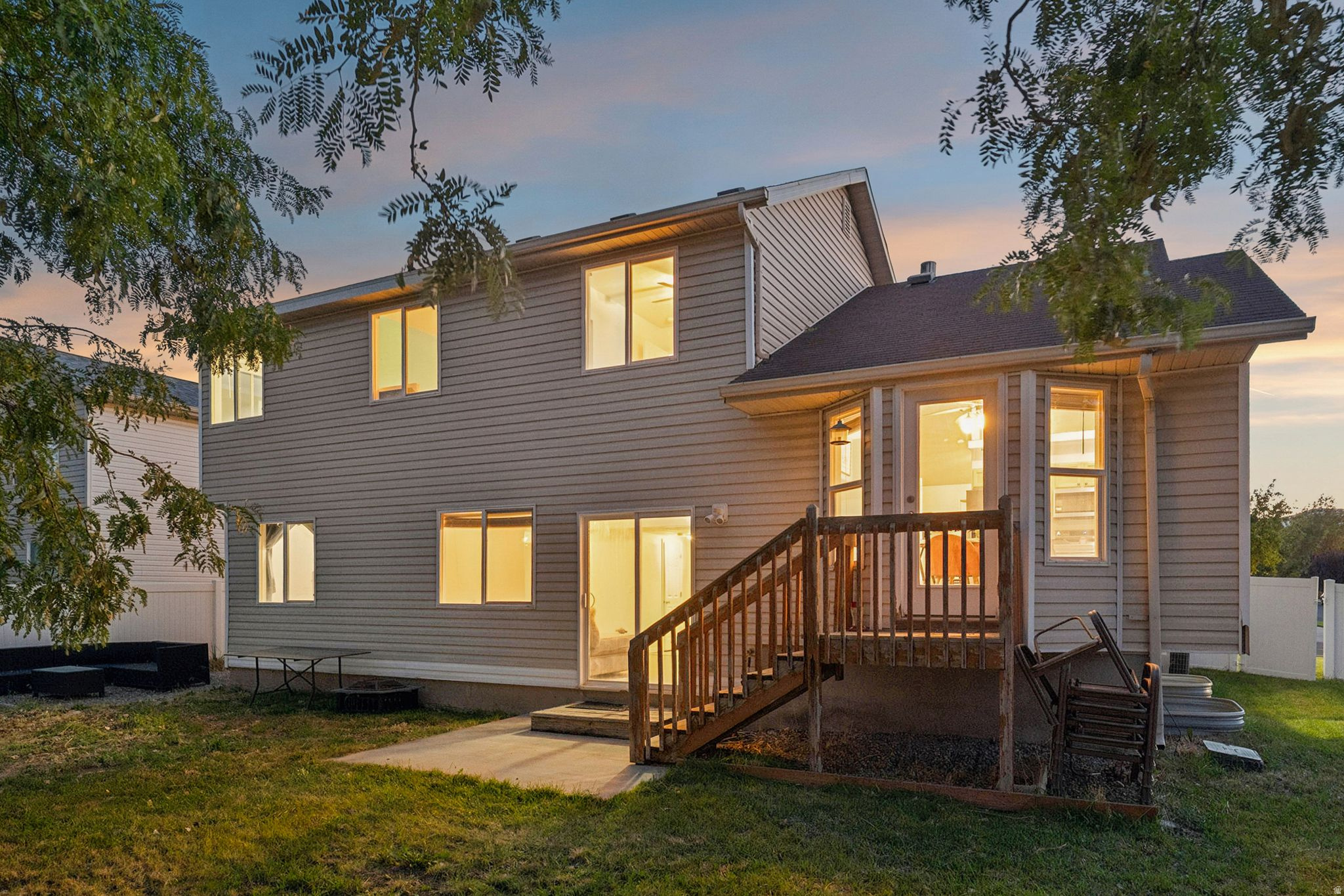 Two-story exterior with siding, featuring multiple windows, a rear deck, and a ground-level patio