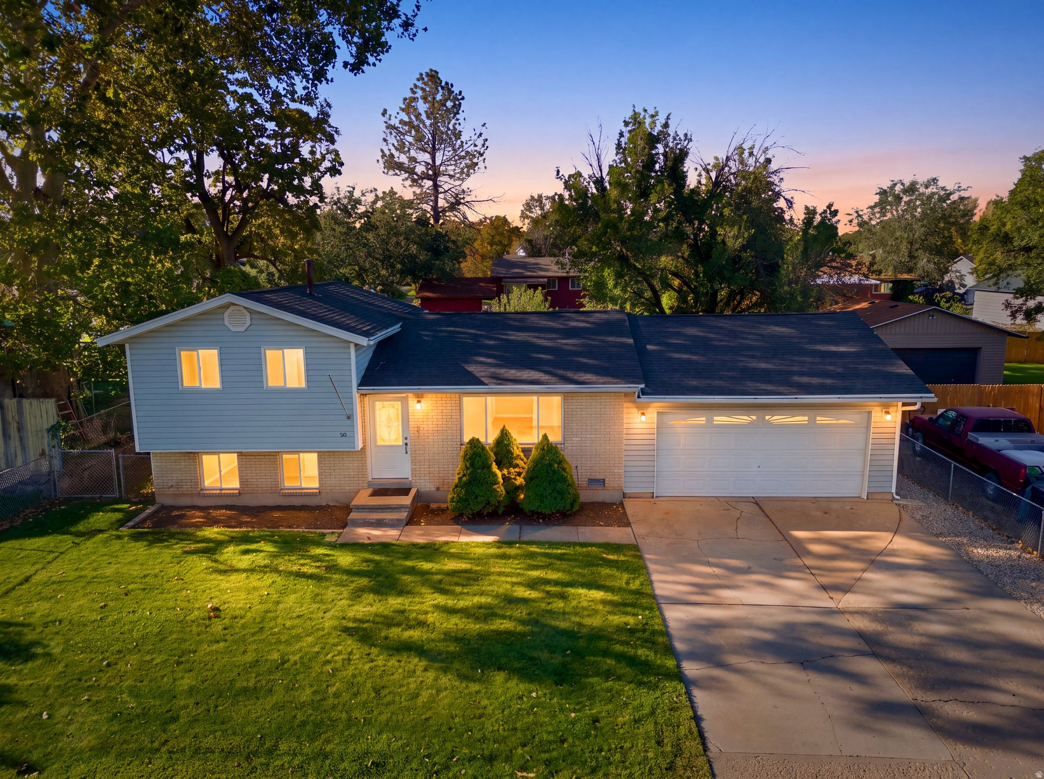 Split-level residence featuring a two-car garage, light-colored siding, and a gabled roof