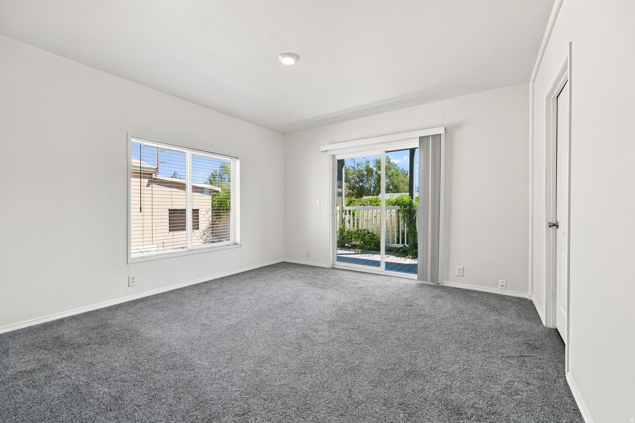 Bright, light-filled bedroom featuring neutral wall finishes, recessed ceiling lighting, and plush carpeting throughout